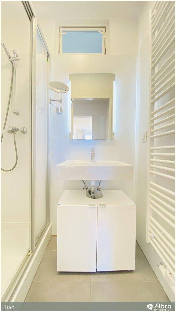 Modernes Badezimmer mit Dusche, Waschtisch und beheiztem Handtuchhalter.