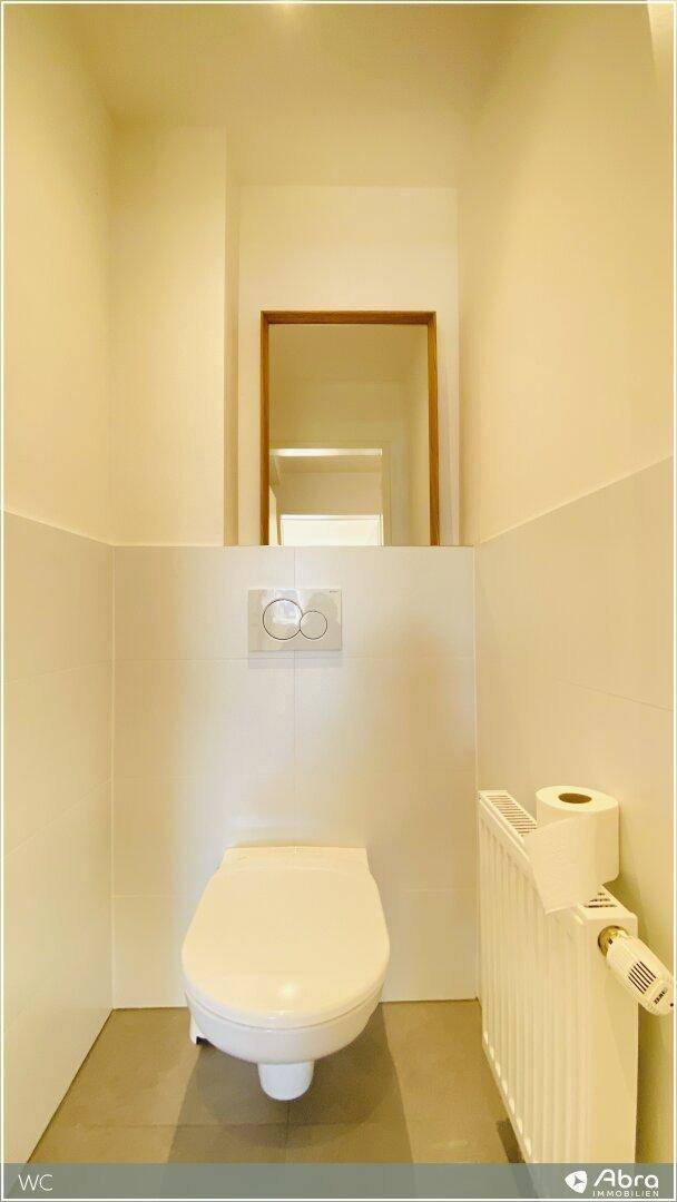 Separates WC mit wandhängender Toilette und Heizkörper.
