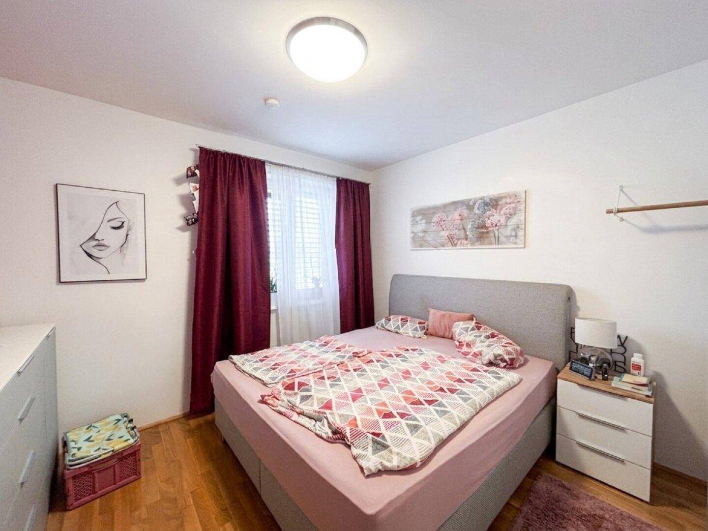 Gemütliches Schlafzimmer mit Doppelbett, Nachttischen und Fenster mit blickdichten Vorhängen.