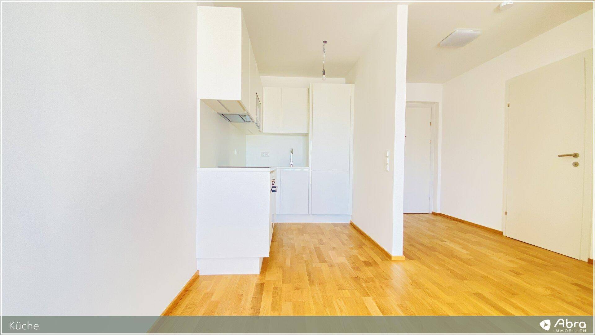 Moderne Küchenzeile mit weißen Schränken, Induktionskochfeld und integriertem Backofen.
