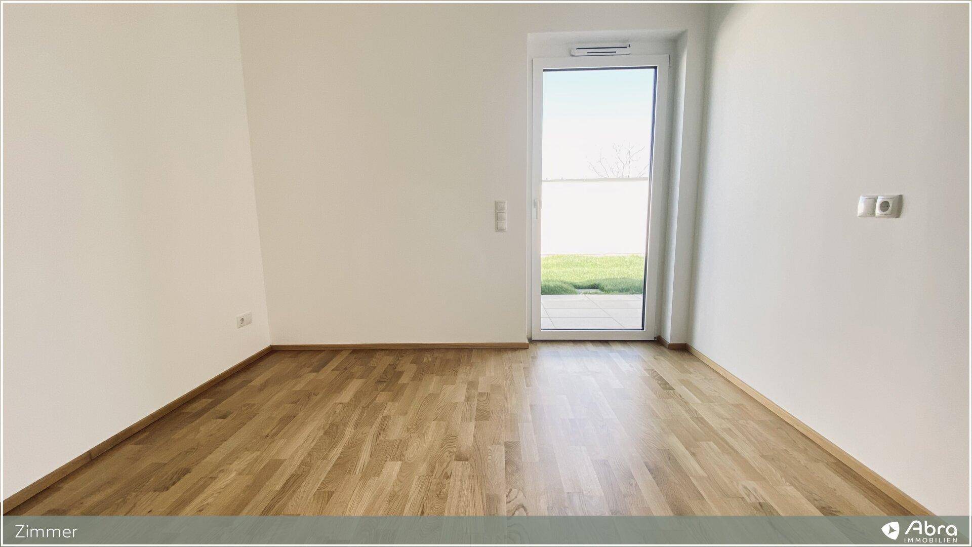 Helles Zimmer mit Zugang zu einem Außenbereich und modernem Holzparkettboden.