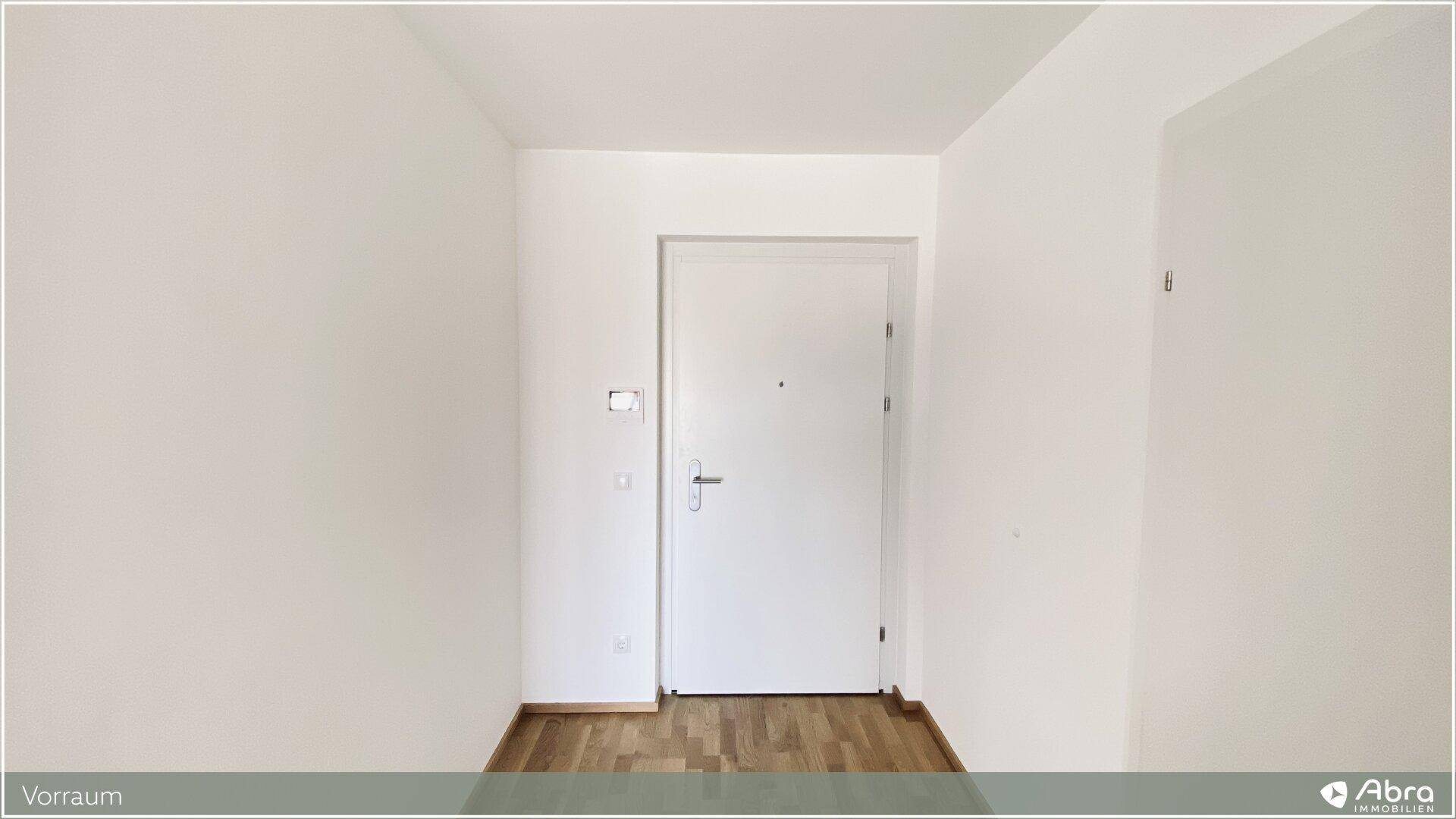 Eingangsbereich mit heller Tür und modernem Holzparkettboden, einladend gestaltet.