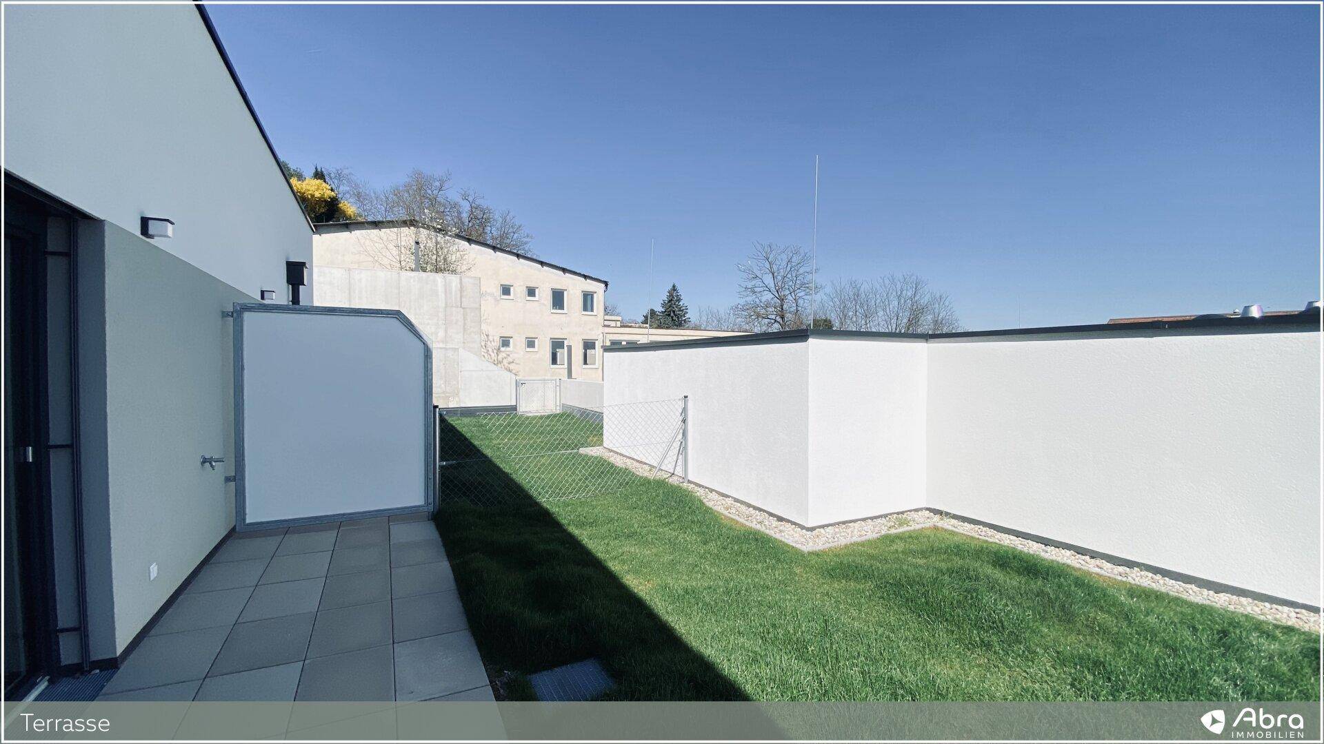 Weitläufige Terrasse mit angrenzendem Gartenbereich und Blick auf die umliegenden Gebäude.