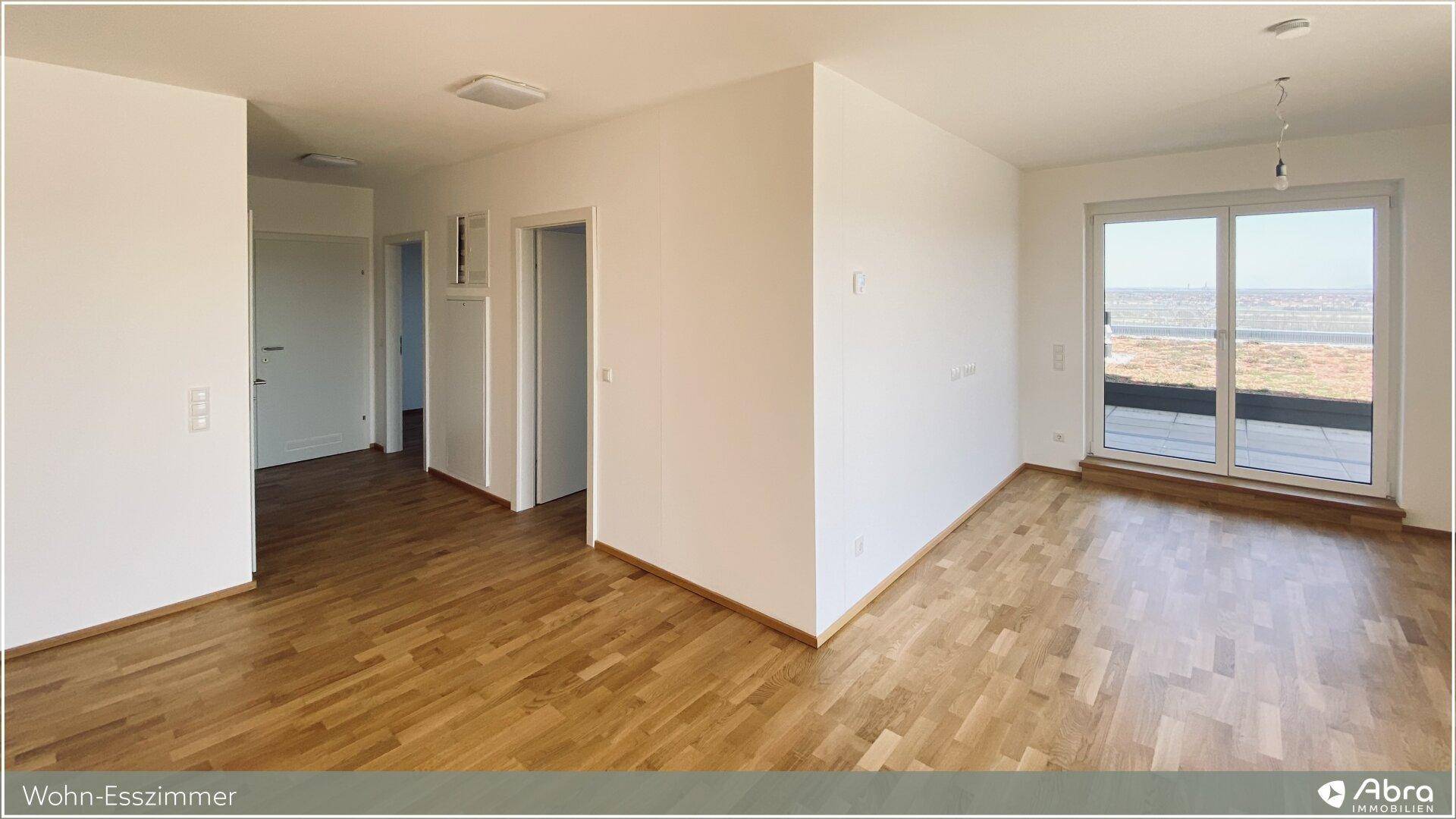 Heller Wohn-Essbereich mit Holzparkett und großen Fenstern, die viel Tageslicht hereinlassen.