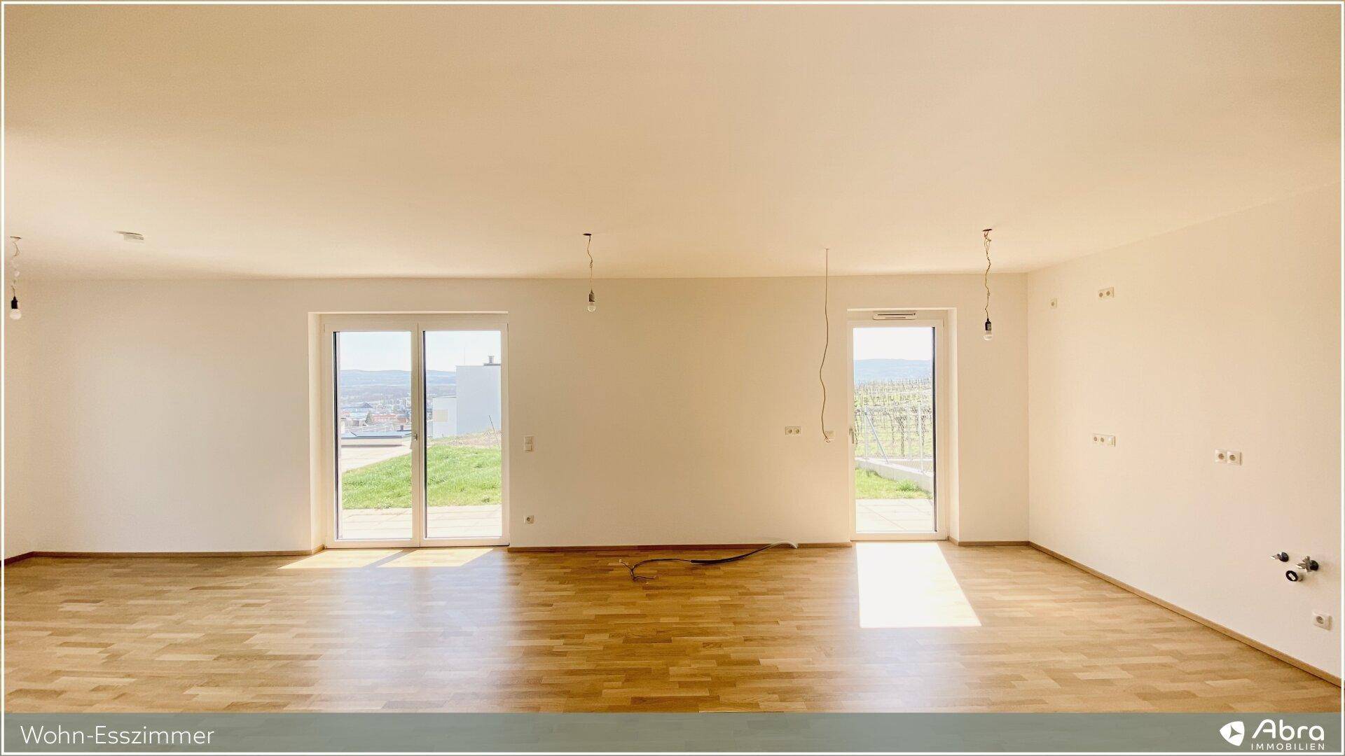 Lichtdurchfluteter Wohn-Essbereich mit zwei großen Terrassentüren und Parkettboden.