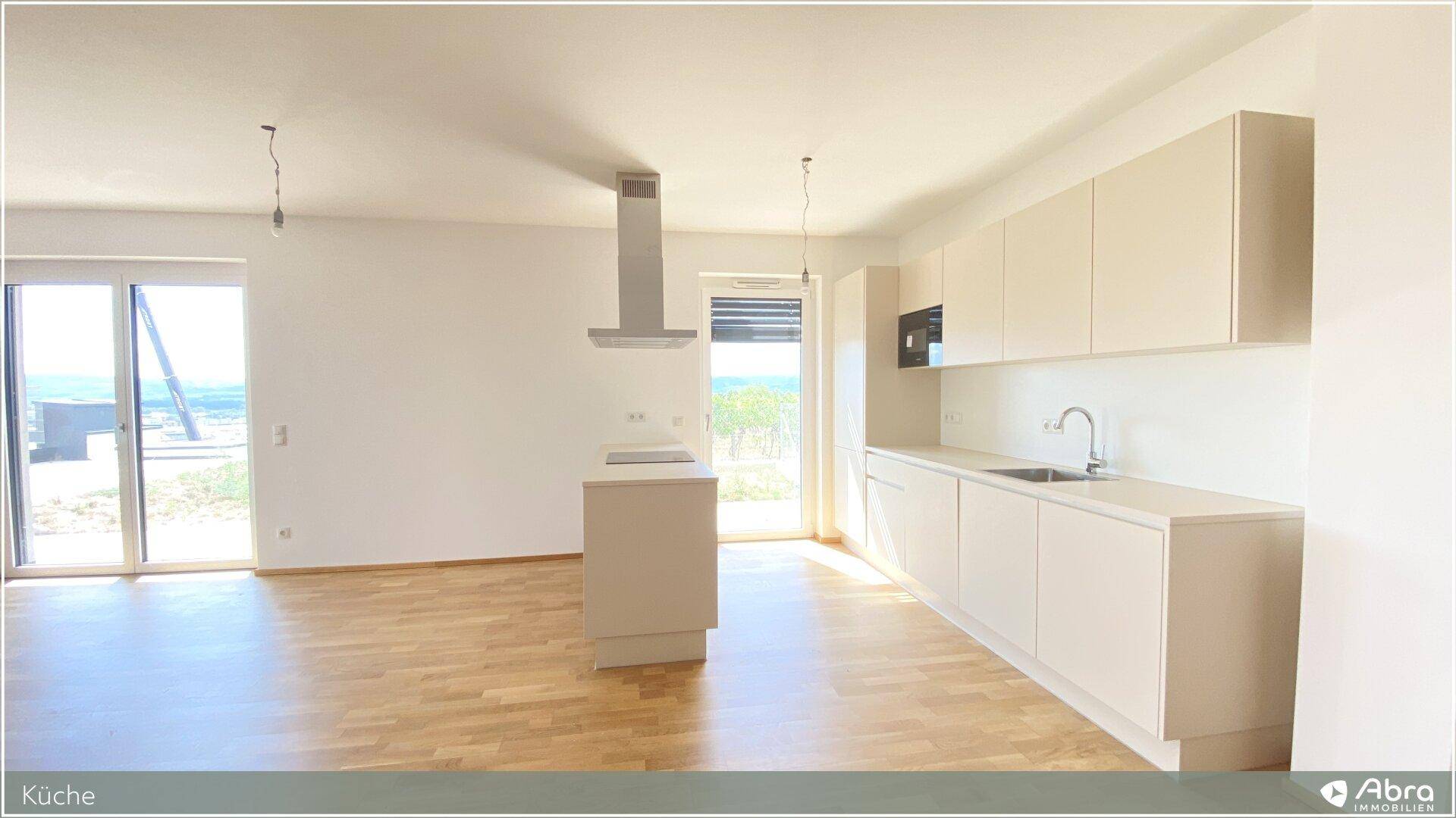 Offene Küche mit Kochinsel, Dunstabzugshaube und hellen Schränken, ideal für geselliges Kochen.
