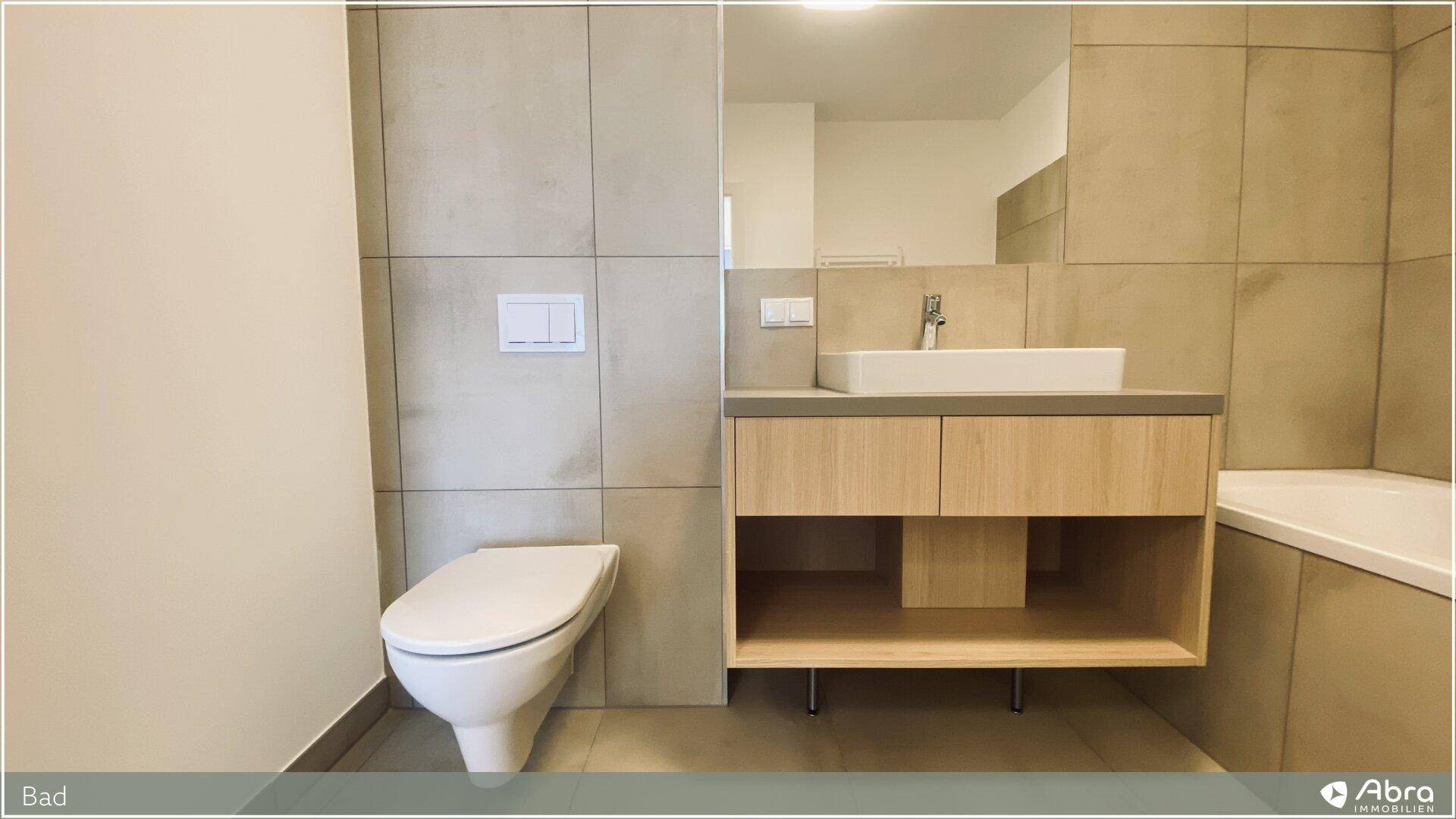 Helles Badezimmer mit Wand-WC, modernem Waschtisch und beigefarbenen Fliesen.