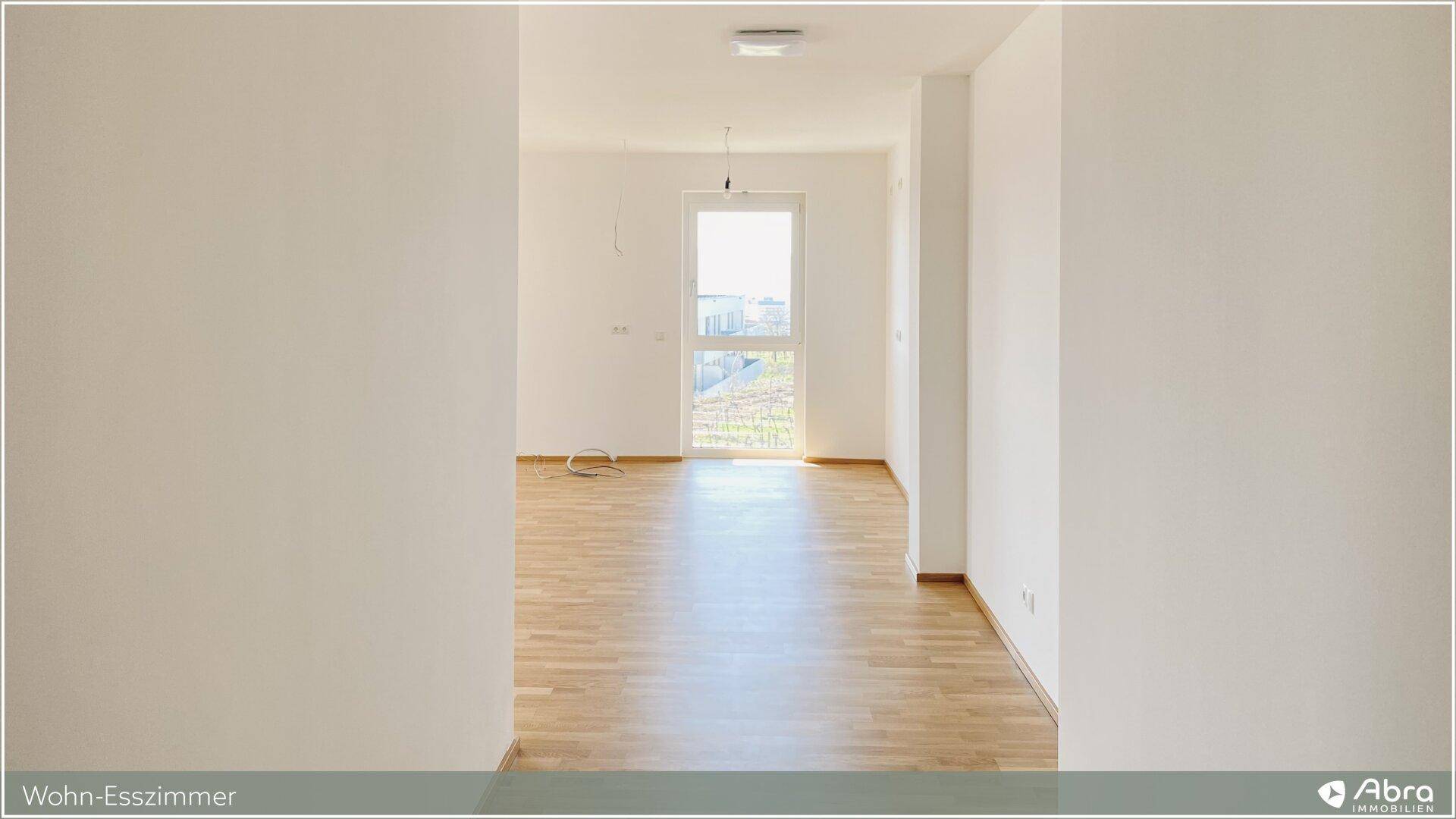 Heller Durchgangsbereich, der in den offenen Wohn-Essbereich mit Parkettboden führt.