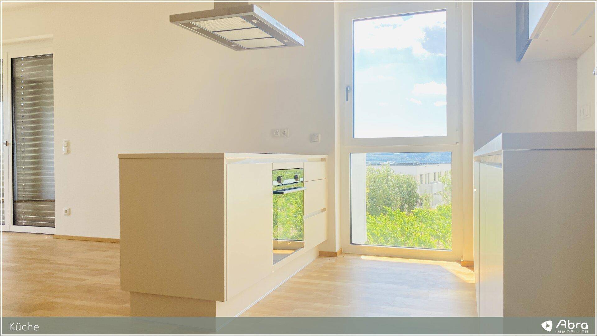 Kücheninsel mit integriertem Backofen und Fenster mit Blick ins Grüne.
