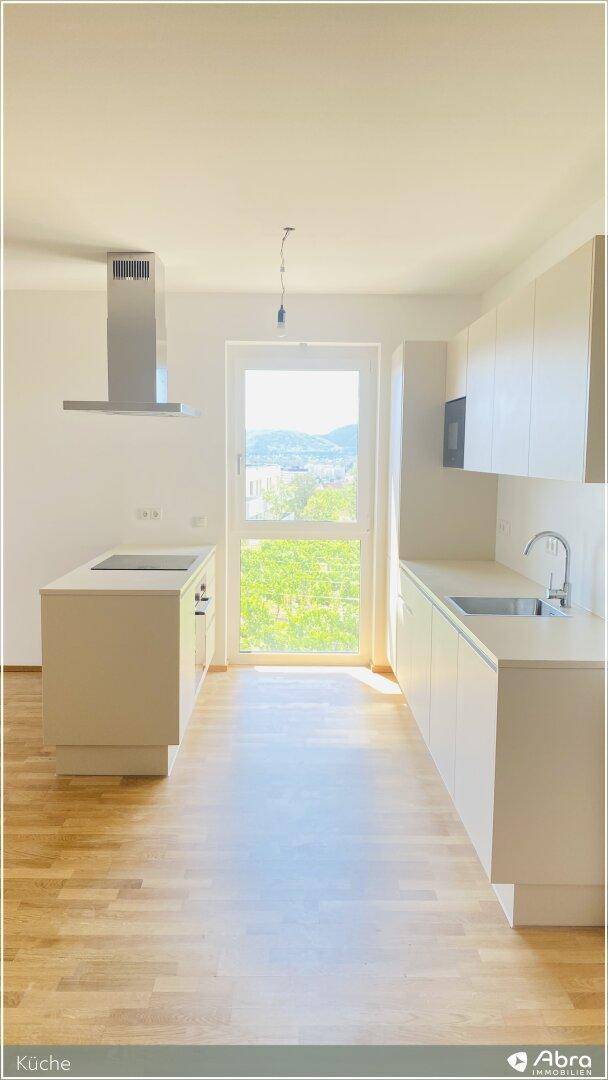 Helle Küche mit moderner Ausstattung, Kücheninsel und großem Fenster für viel Tageslicht.