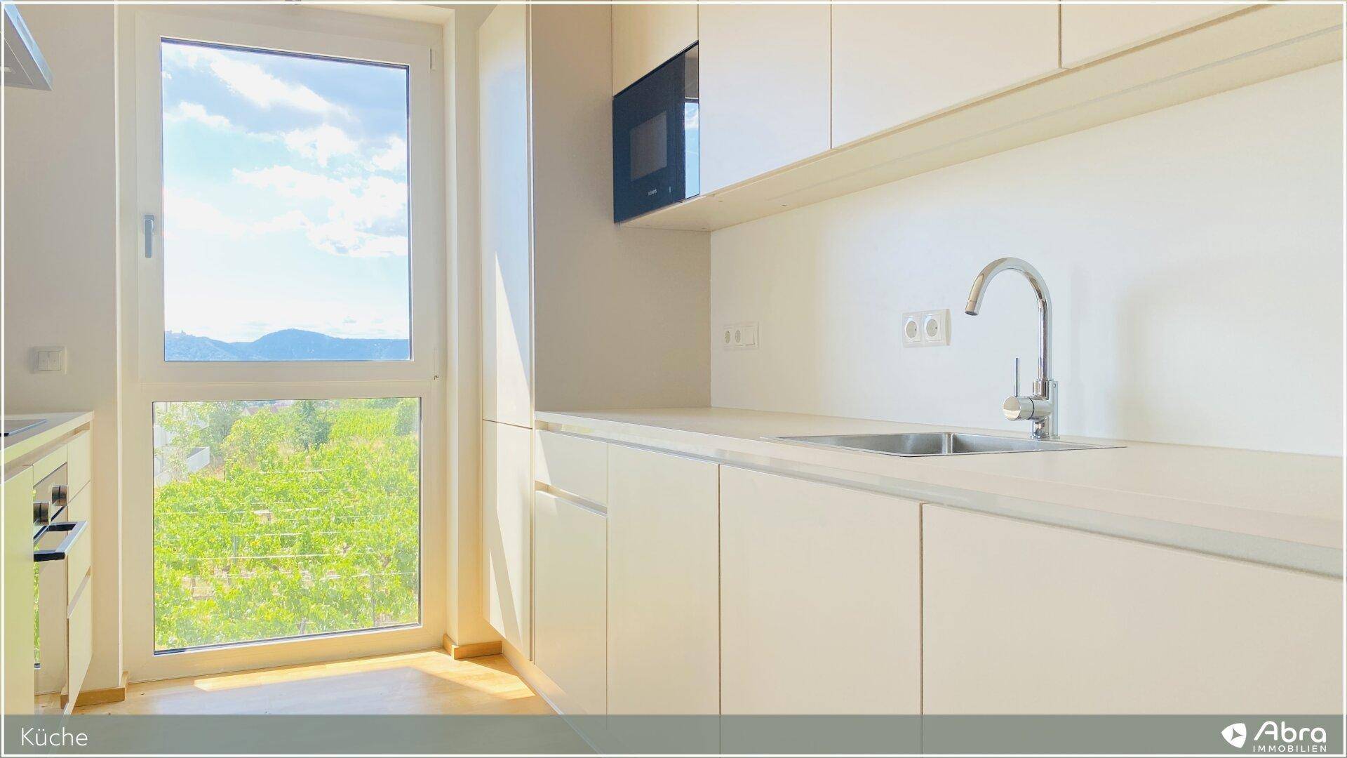 Küchenzeile mit Spülbecken und Fenster, das einen schönen Blick ins Grüne bietet.