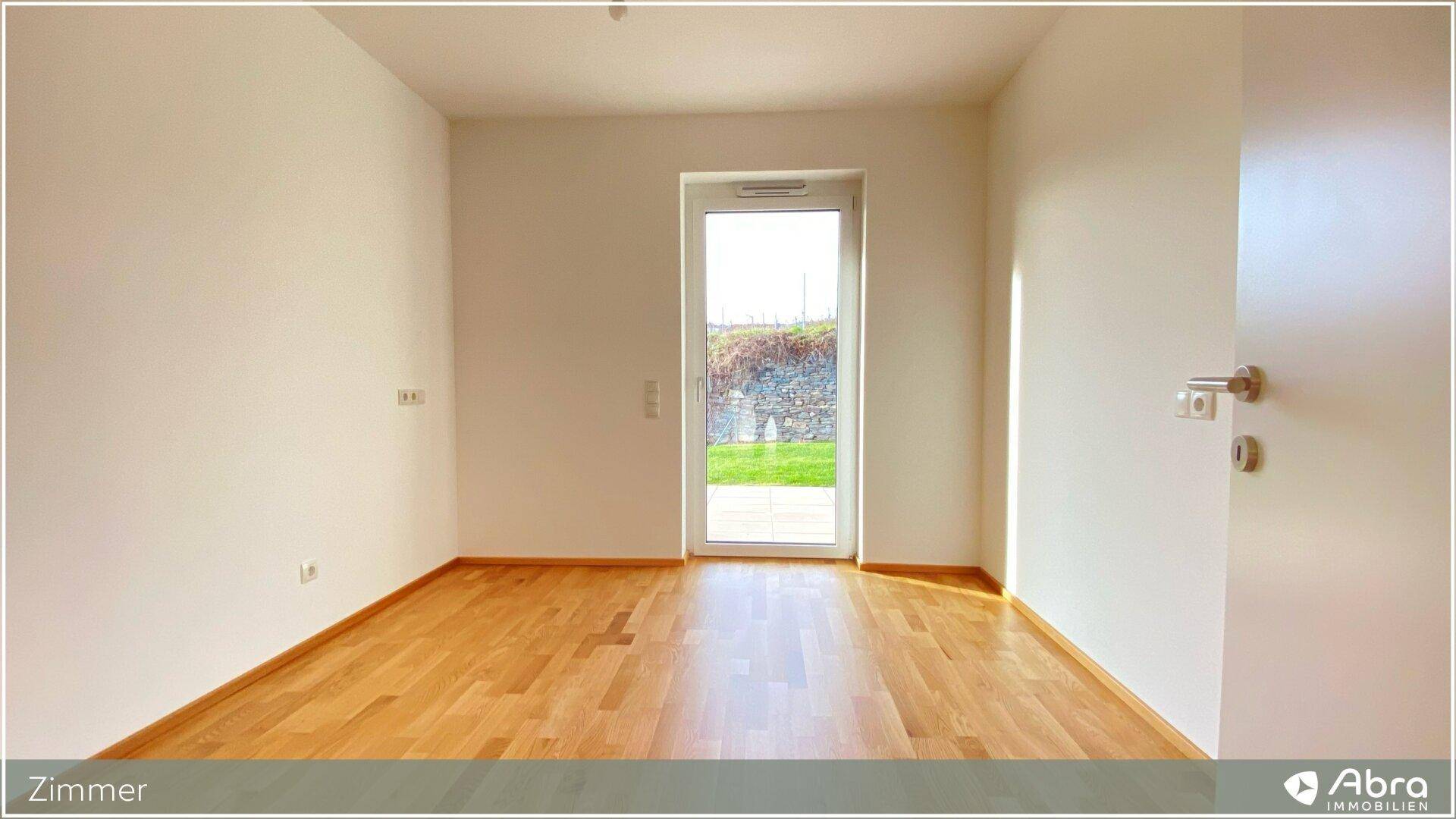 Helles Zimmer mit Parkettboden und direktem Zugang zu einem Garten oder einer Terrasse.