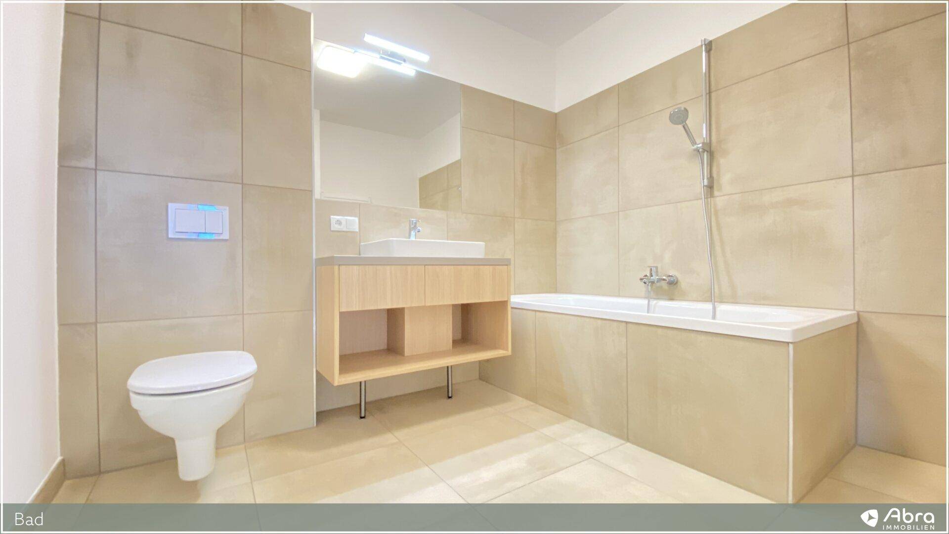 Komplettes Badezimmer mit Badewanne, Waschtisch und wandhängendem WC in hellen Fliesen.