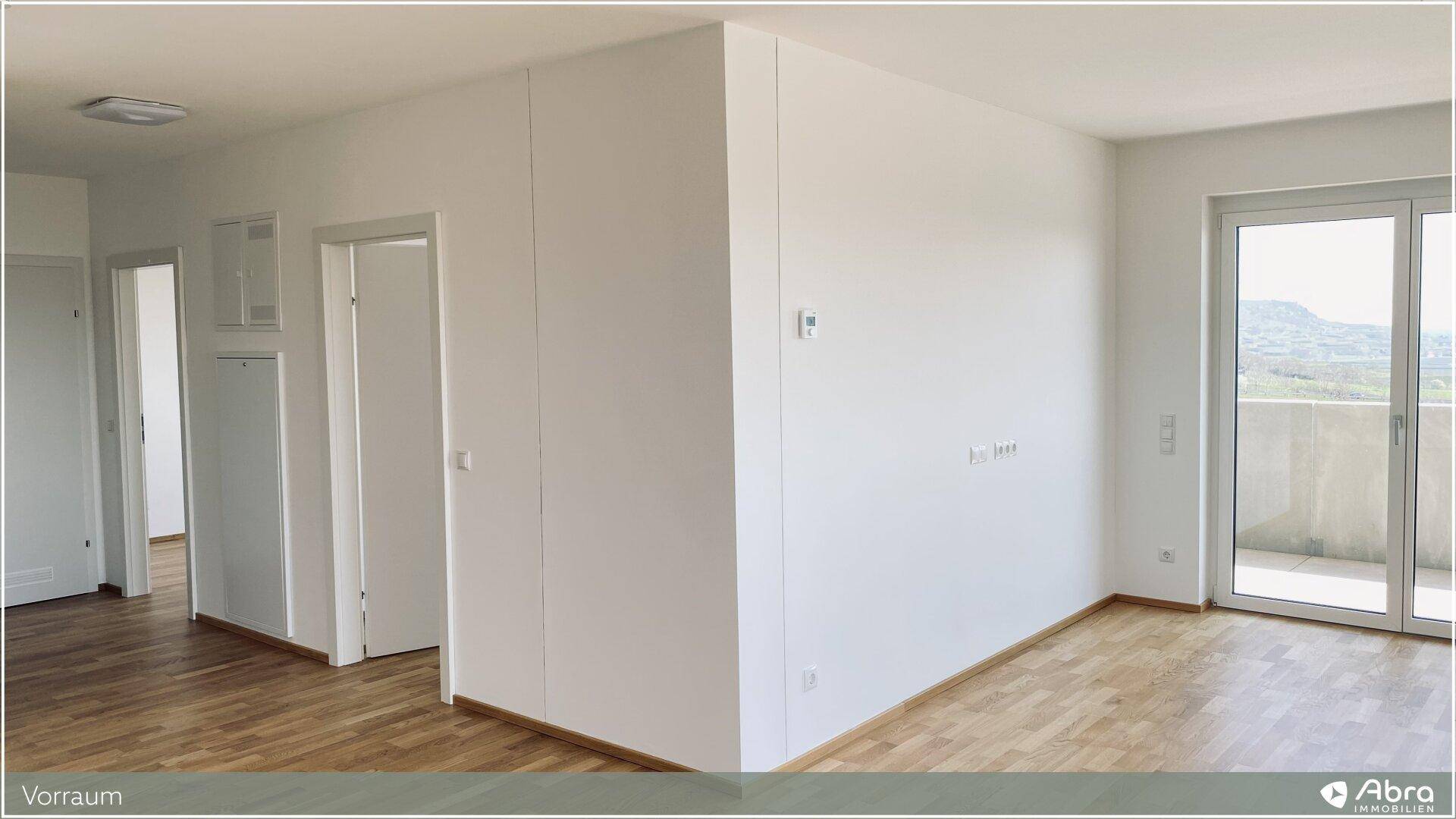 Geräumiger, heller Wohnbereich mit Holzparkettboden und Zugang zu einem Balkon oder einer Terrasse.
