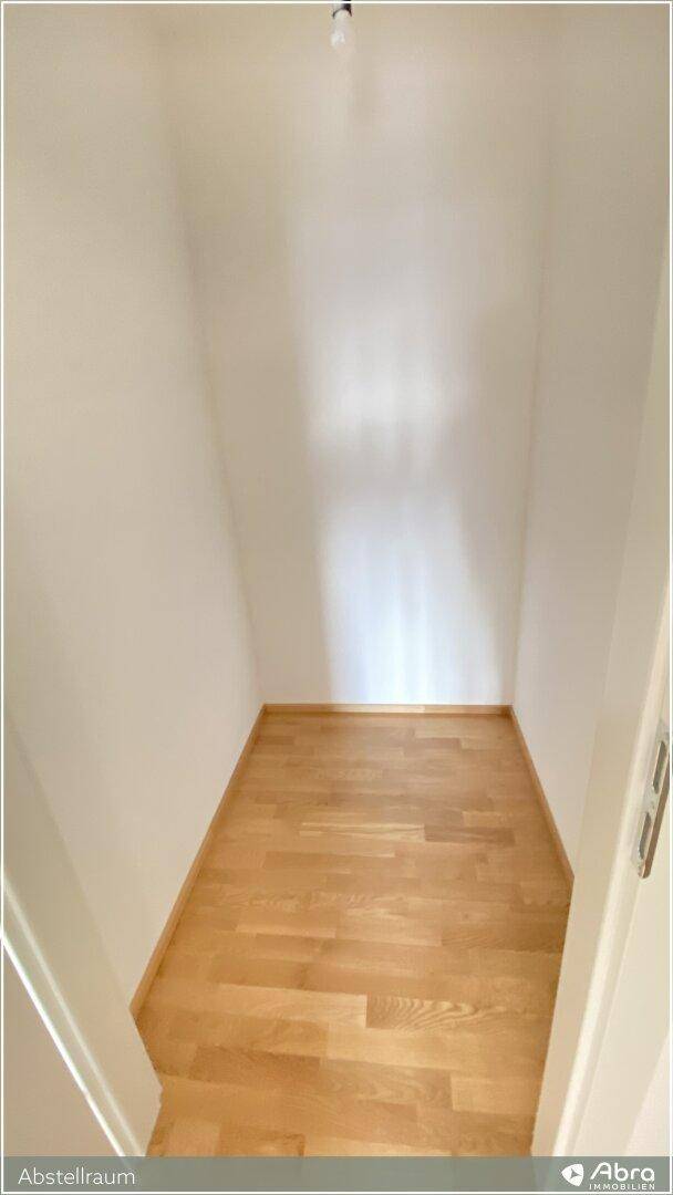 Kleiner, leerer Abstellraum mit hellem Holzparkettboden und weißen Wänden.
