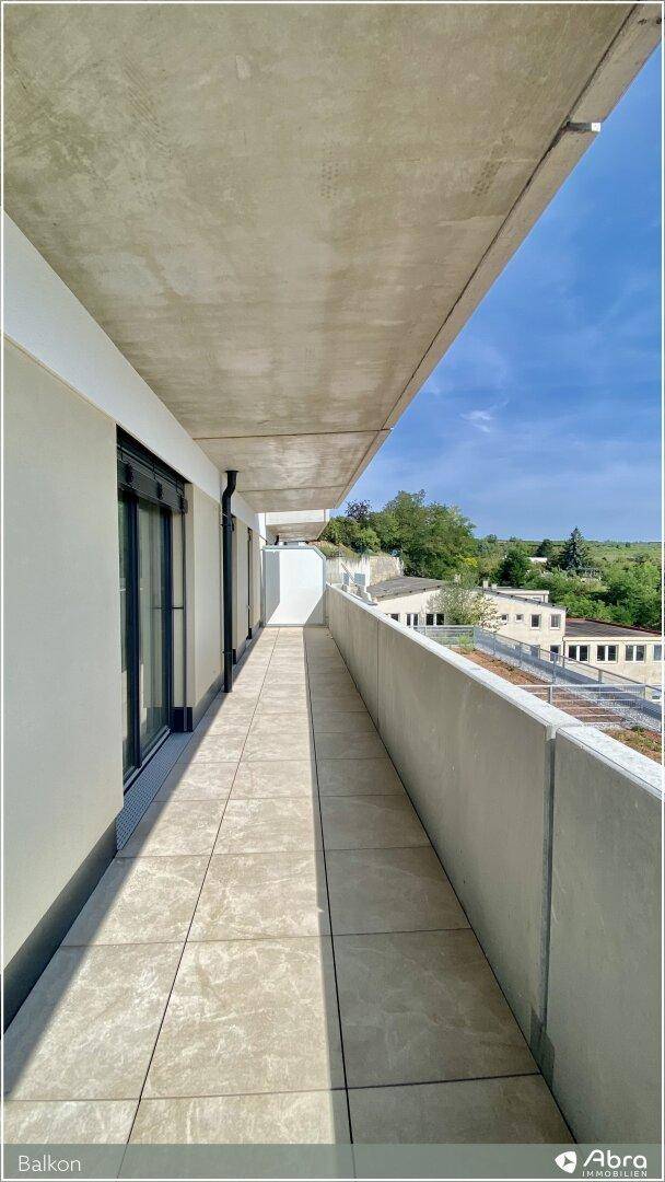 Langer, gefliester Balkon mit Betonbrüstung und weitem Blick über die Umgebung.