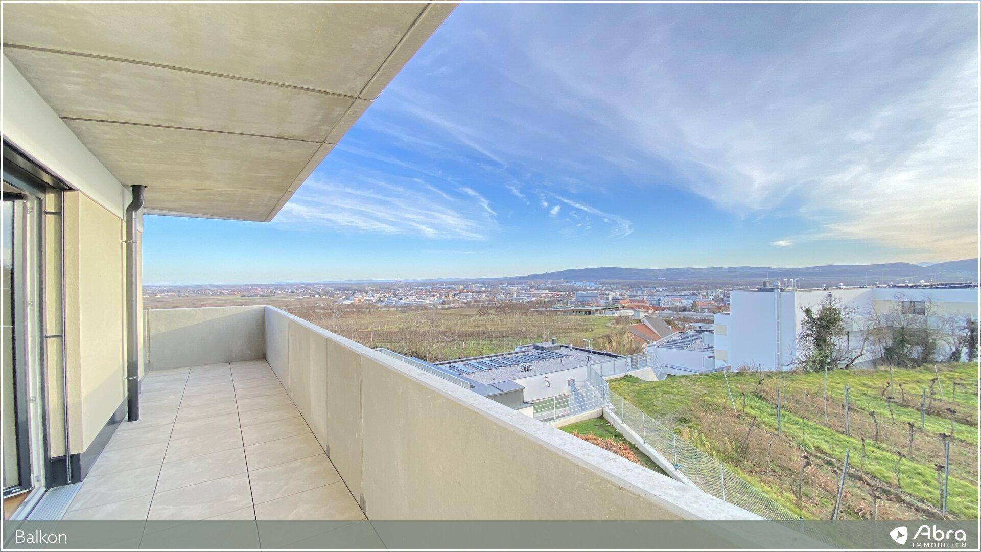 Großer Balkon mit Fliesenboden und weitem Panoramablick über Weinberge und die Stadt.