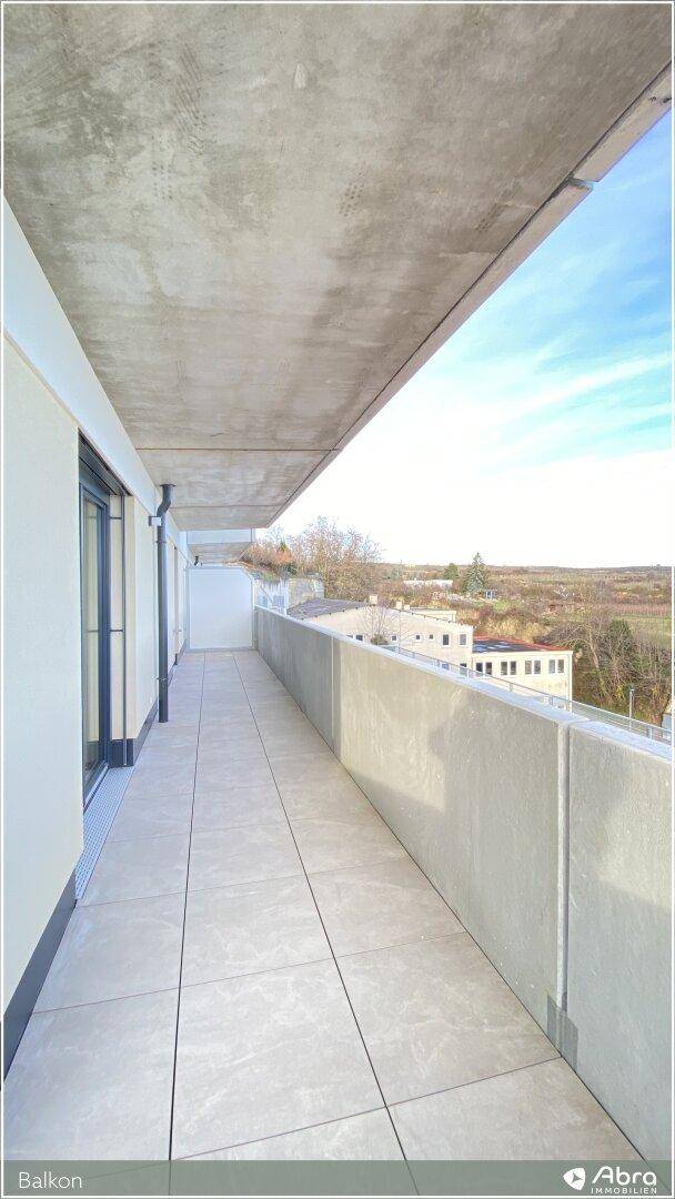 Heller Balkon mit Fliesenboden und Betonbrüstung, bietet einen weiten Blick in die Landschaft.