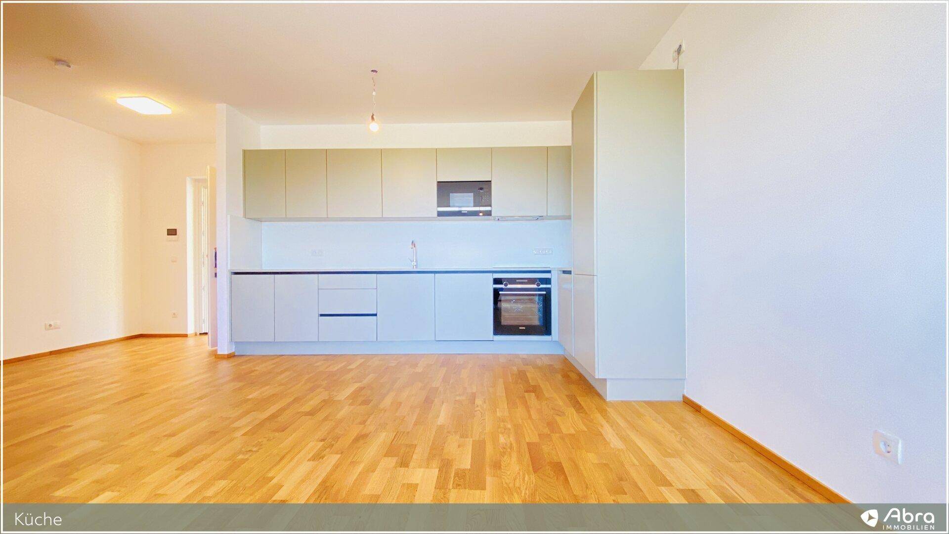 Moderne Einbauküche mit hellen Fronten, integrierten Geräten und Parkettboden.