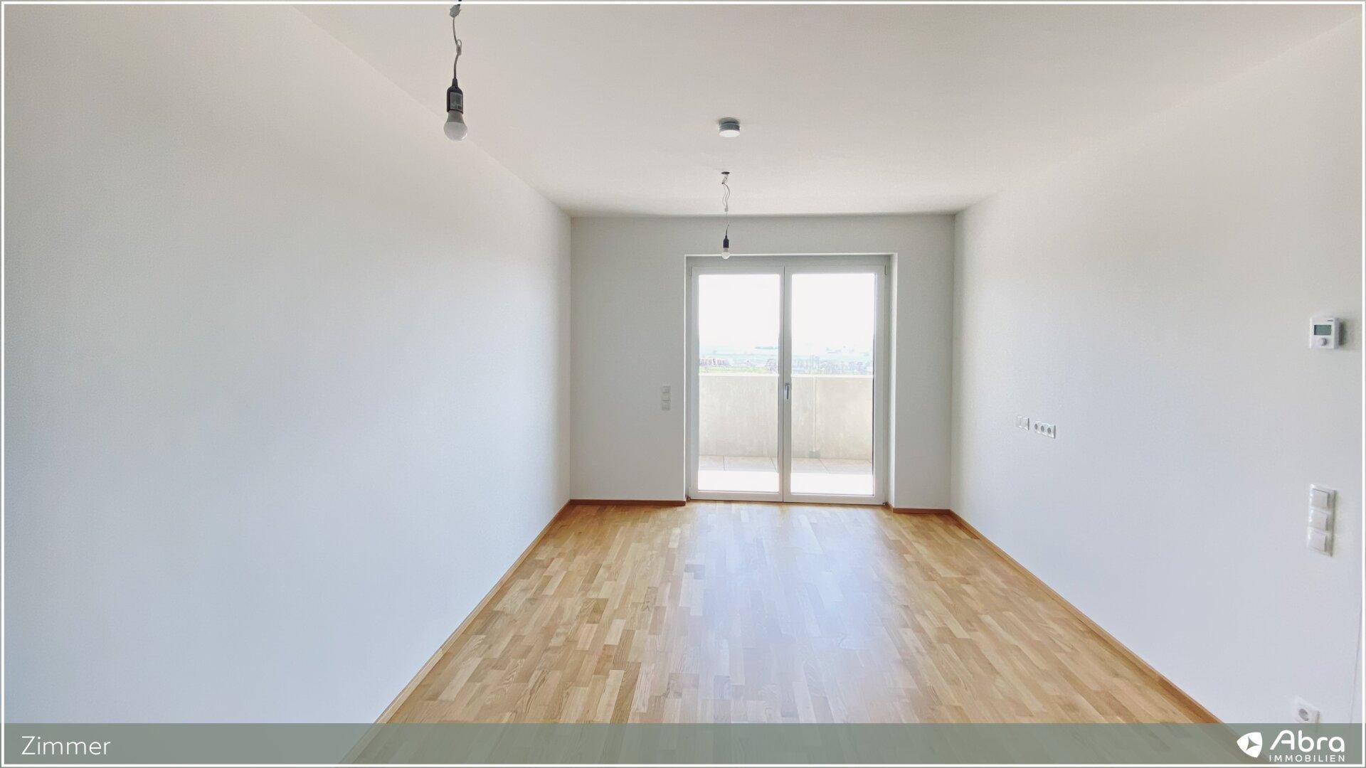 Helles Zimmer mit Parkettboden und direktem Zugang zum Balkon.