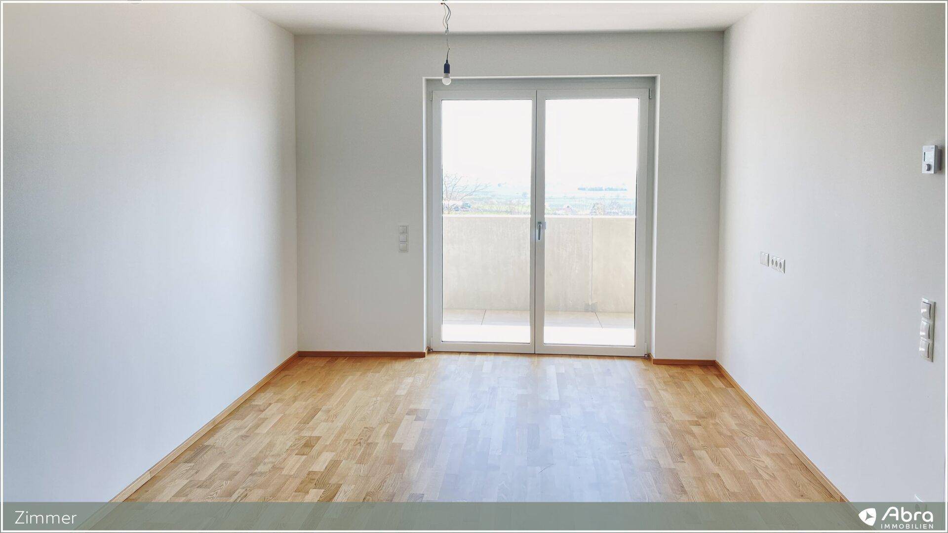 Helles Zimmer mit Parkettboden und direktem Zugang zum Balkon.