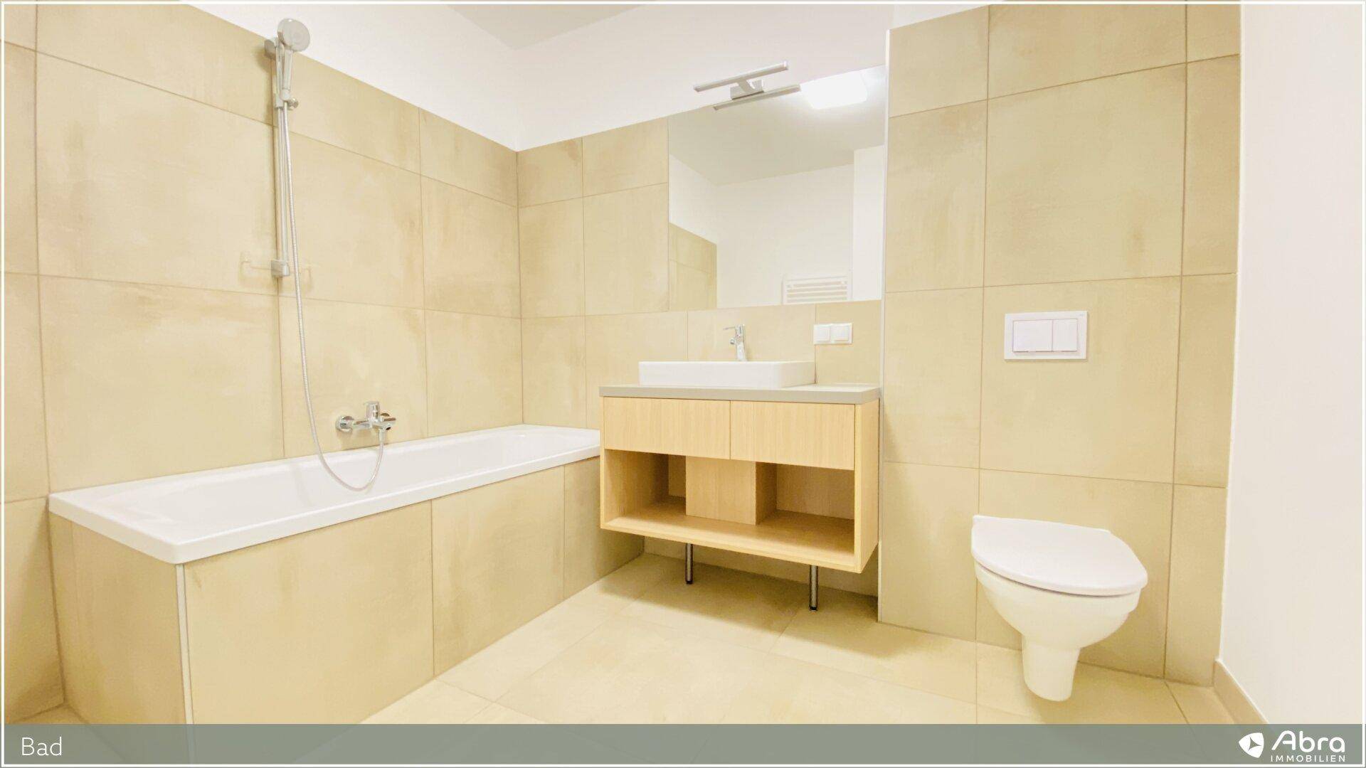 Geräumiges Badezimmer mit Badewanne, Waschtisch und WC in neutralen Farbtönen.