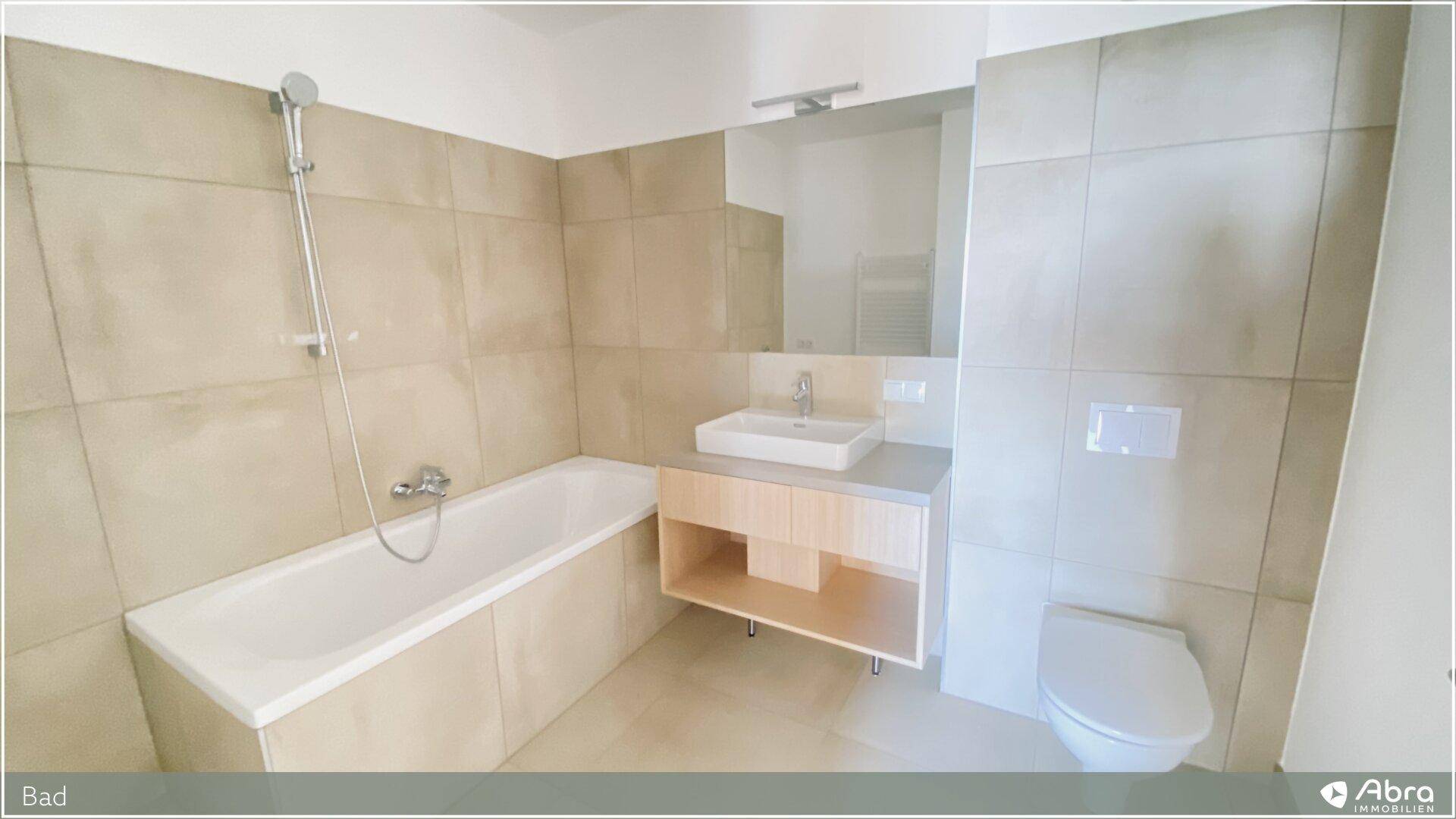 Modernes Badezimmer mit Badewanne, Waschtisch und WC, ausgestattet mit hellen Fliesen.