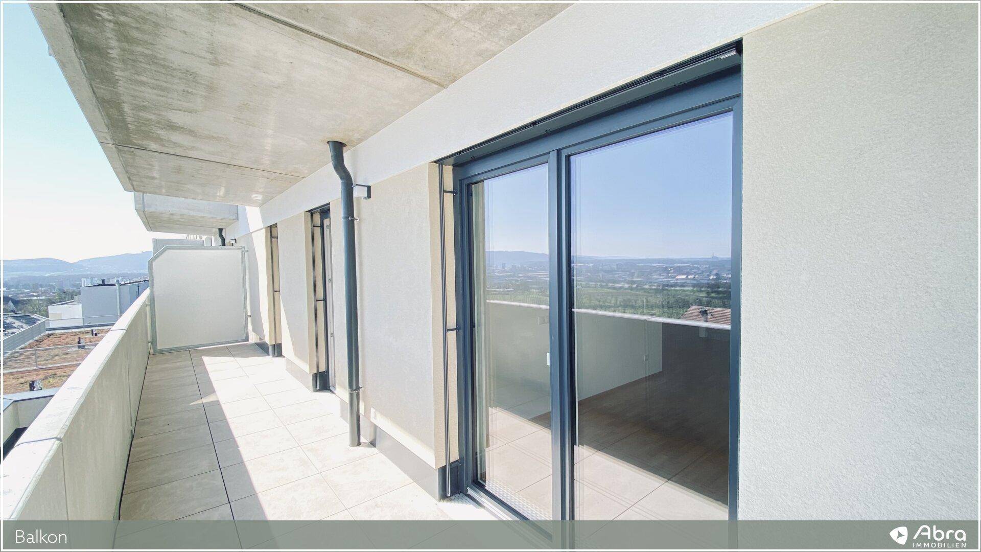 Breiter Balkon mit Schiebetüren und Blick auf die umliegende Landschaft.
