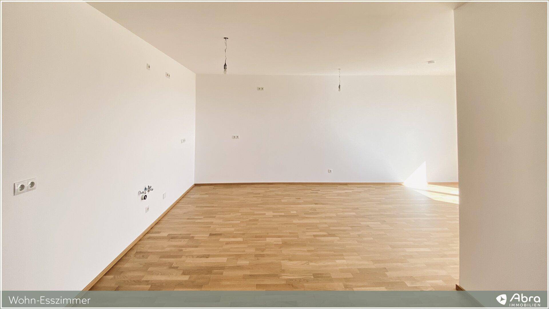 Geräumiger, unmöblierter Wohn-Essbereich mit Parkettboden und hellen Wänden, bereit zur individuellen Gestaltung.