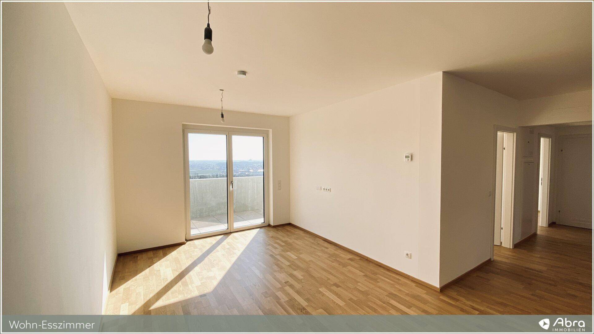 Sonniger Wohn-Essbereich mit Parkettboden und Zugang zu einem Außenbereich, ideal für Entspannung.