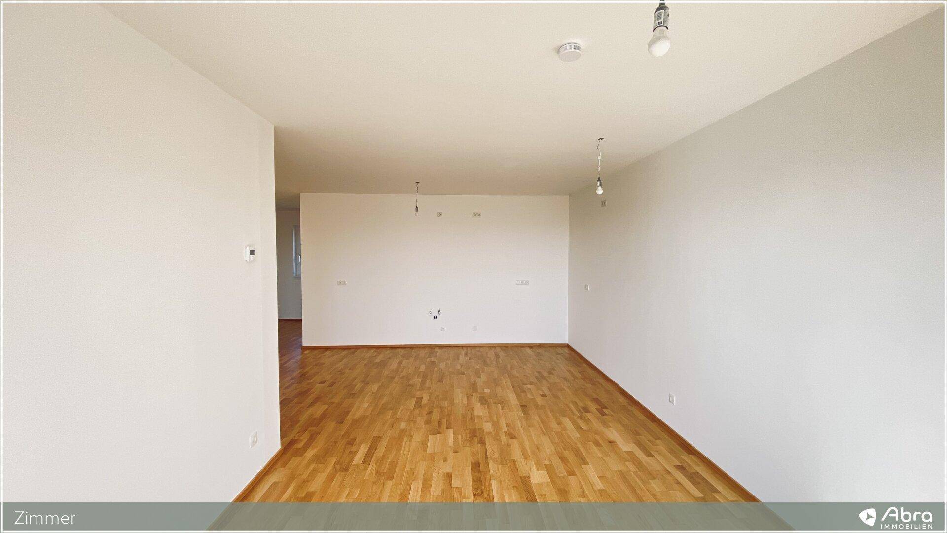 Geräumiges, unmöbliertes Zimmer mit Parkettboden und hellen Wänden, vielseitig nutzbar.