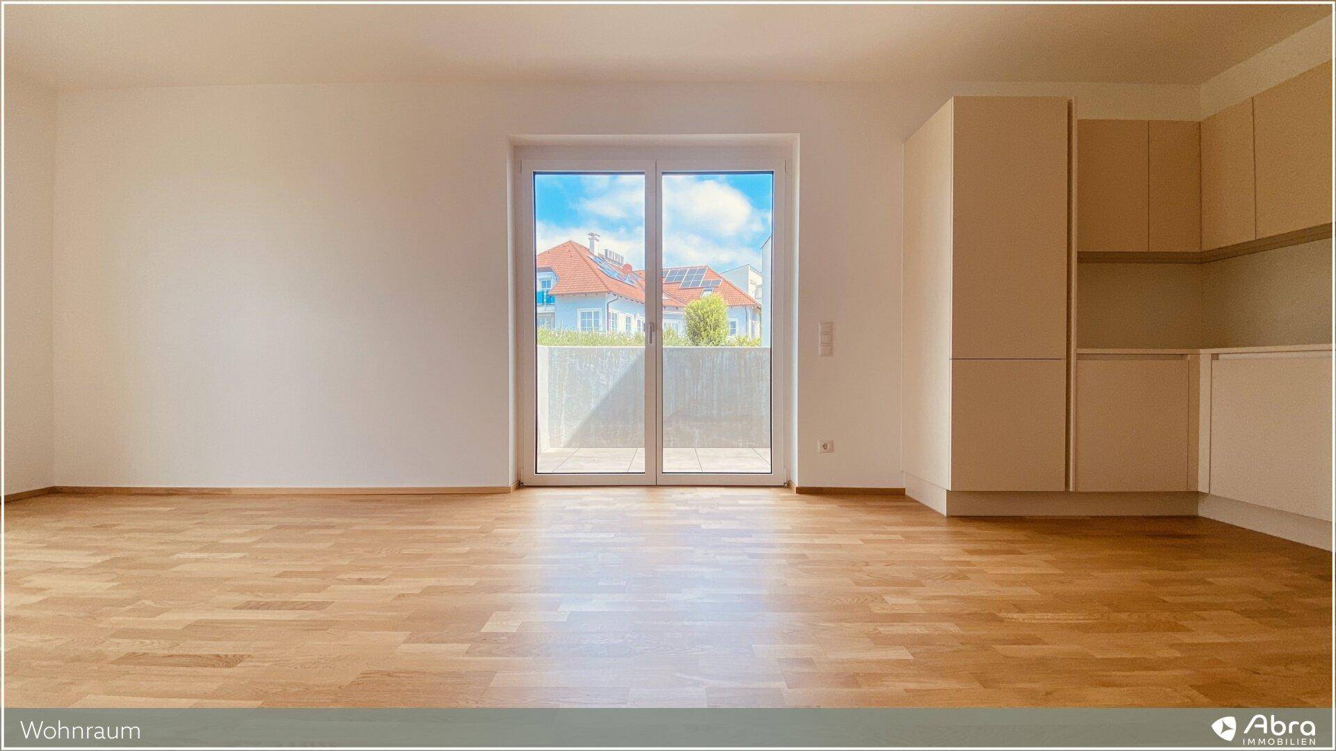 Lichtdurchfluteter Wohnbereich mit Holzboden und großer Terrassentür, die viel Tageslicht hereinlässt.