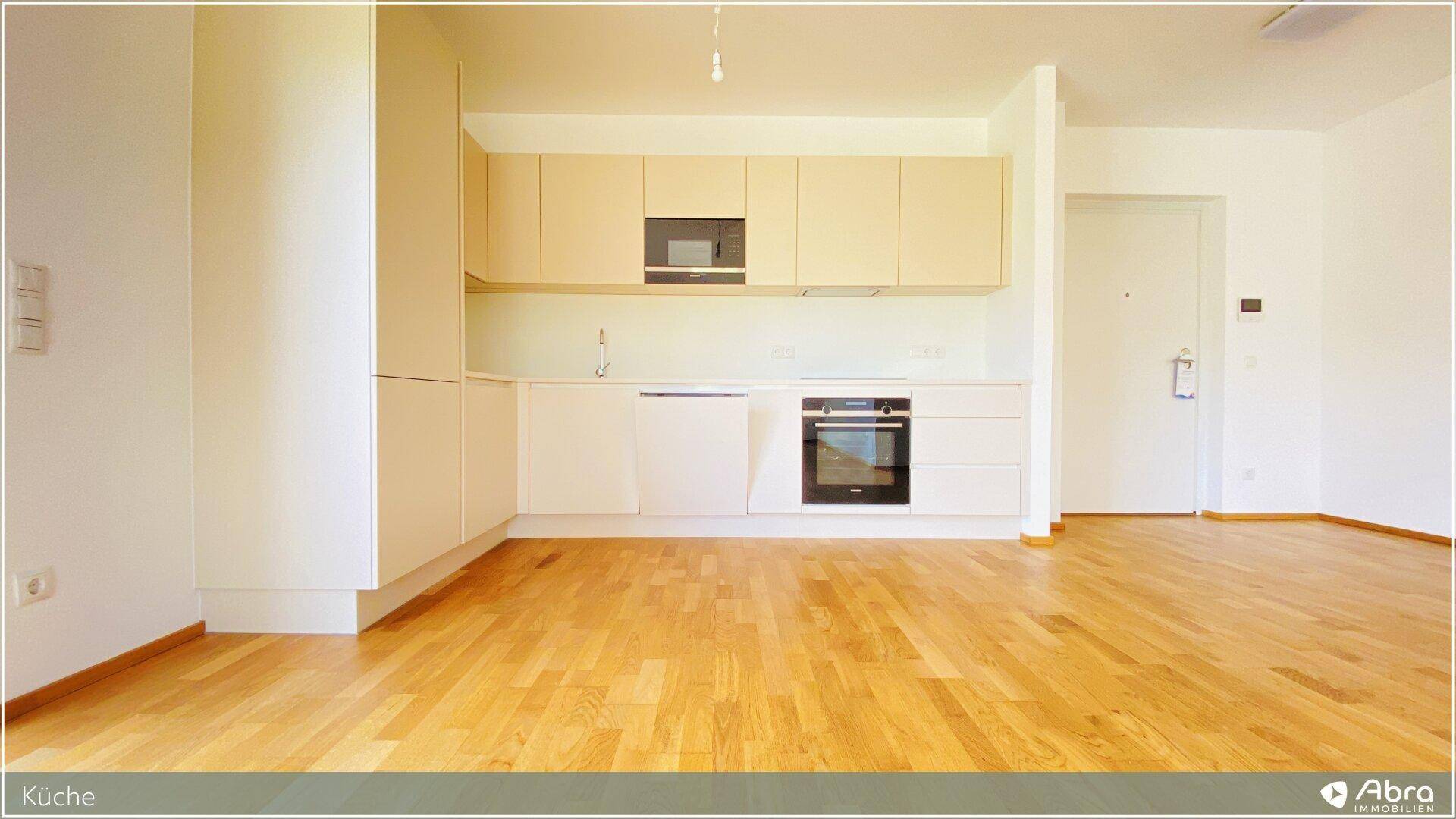 Moderne Einbauküche in hellem Design mit integrierten Geräten und Holzboden.
