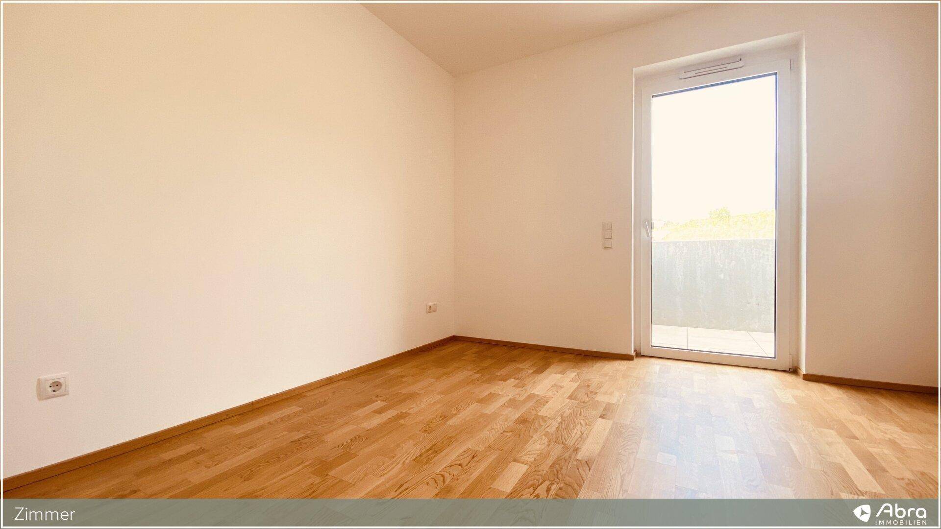 Freundliches Zimmer mit Holzboden und direktem Zugang zu einem Außenbereich.