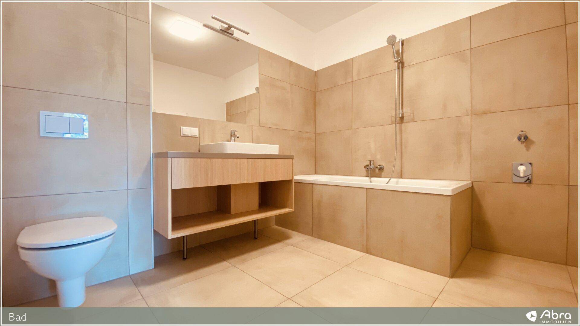 Funktionelles Badezimmer mit Wand-WC, Waschtisch und Badewanne, ausgestattet mit modernen Armaturen.