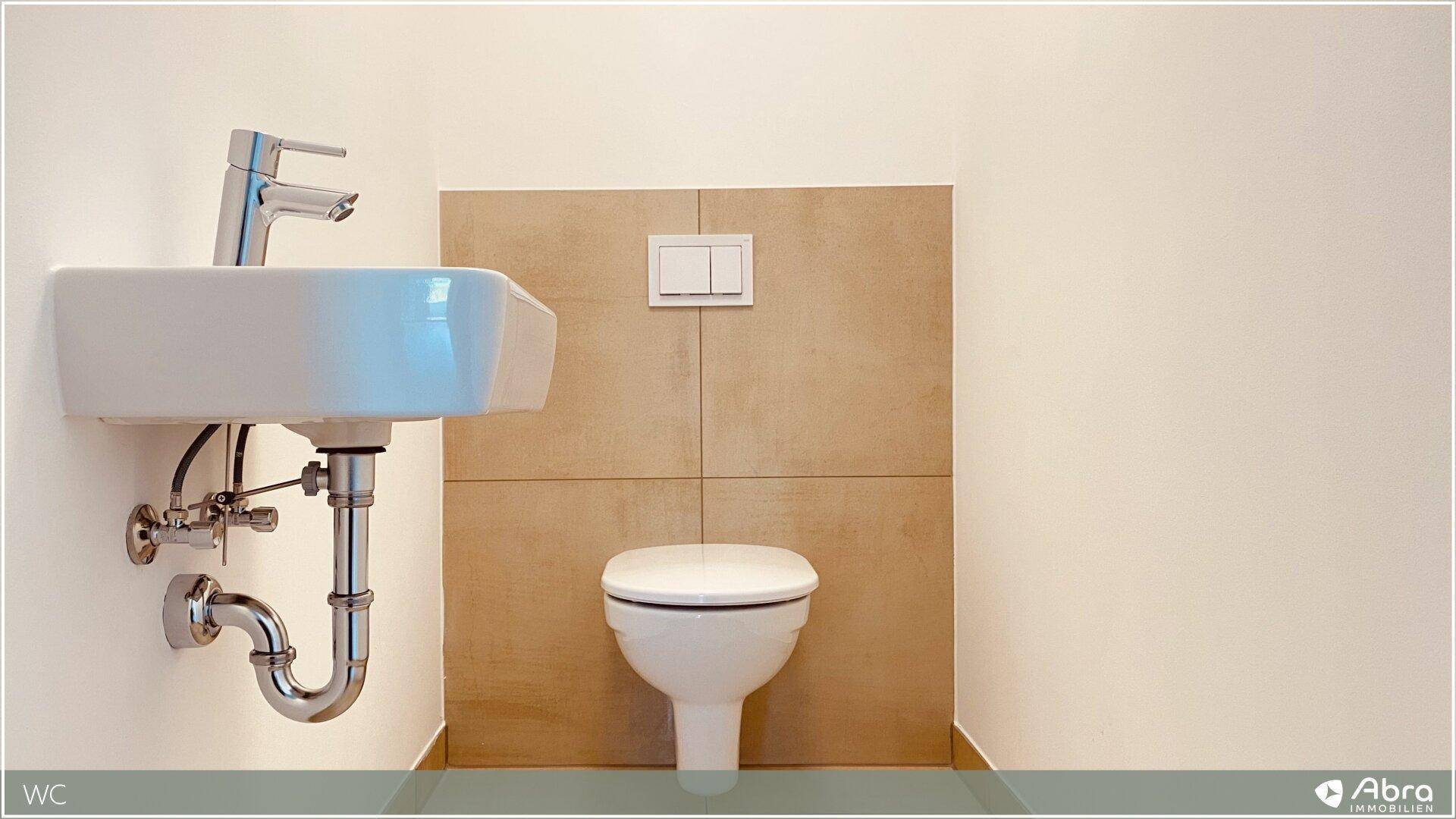 Separates Gäste-WC mit Wand-WC und modernem Handwaschbecken, teilweise gefliest.