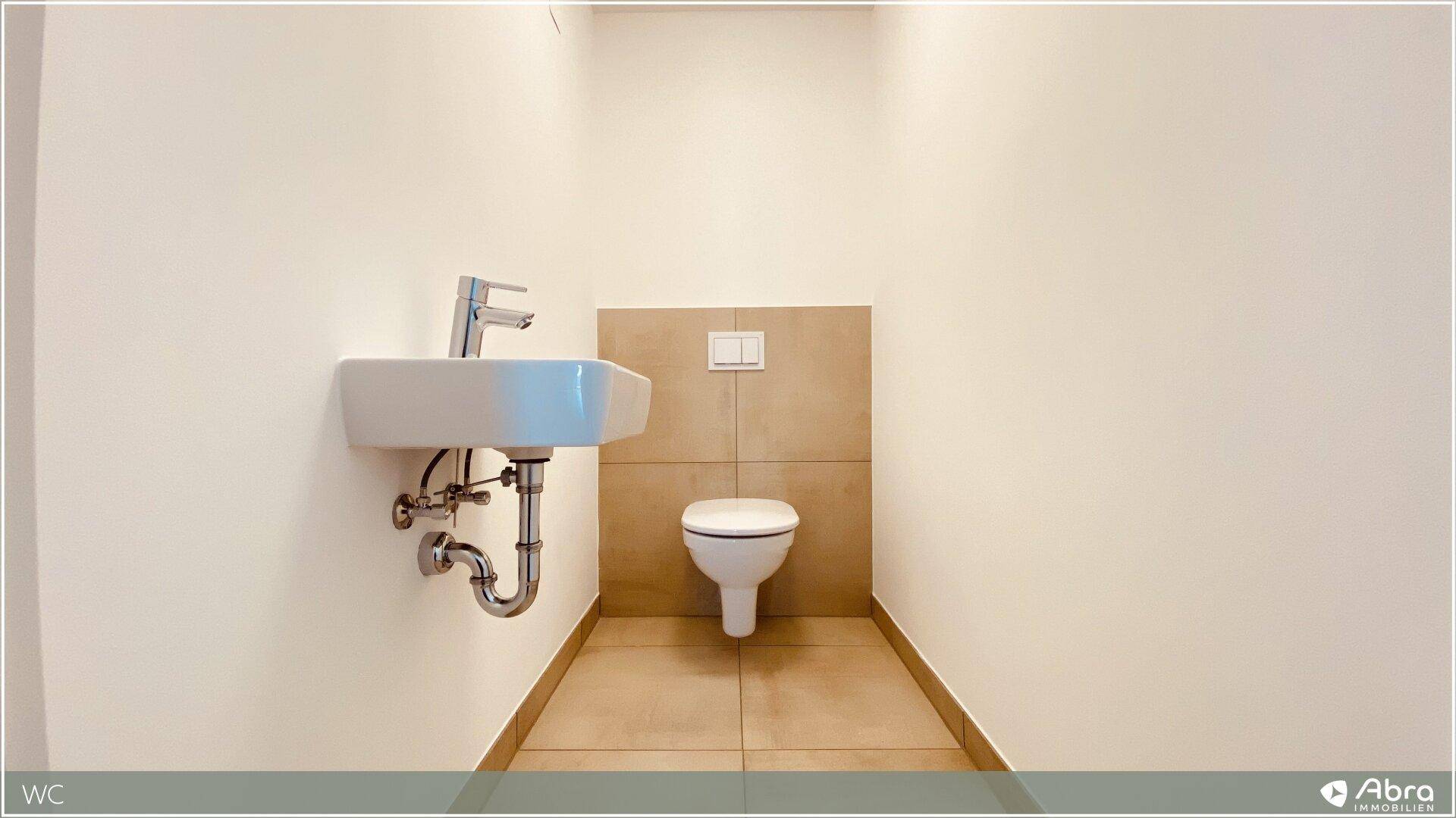 Kleines, aber funktionales Gäste-WC mit Wand-WC und Handwaschbecken, in hellen Farben gehalten.