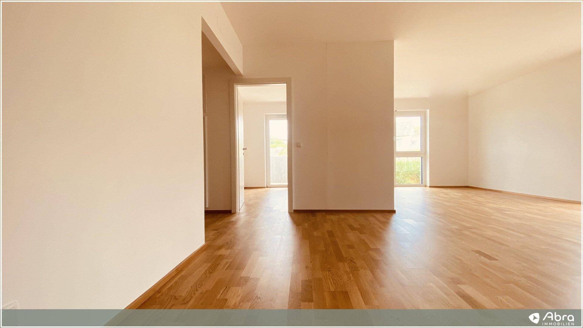 Heller, leerer Raum mit neuem Holzparkettboden und großen Fenstern.