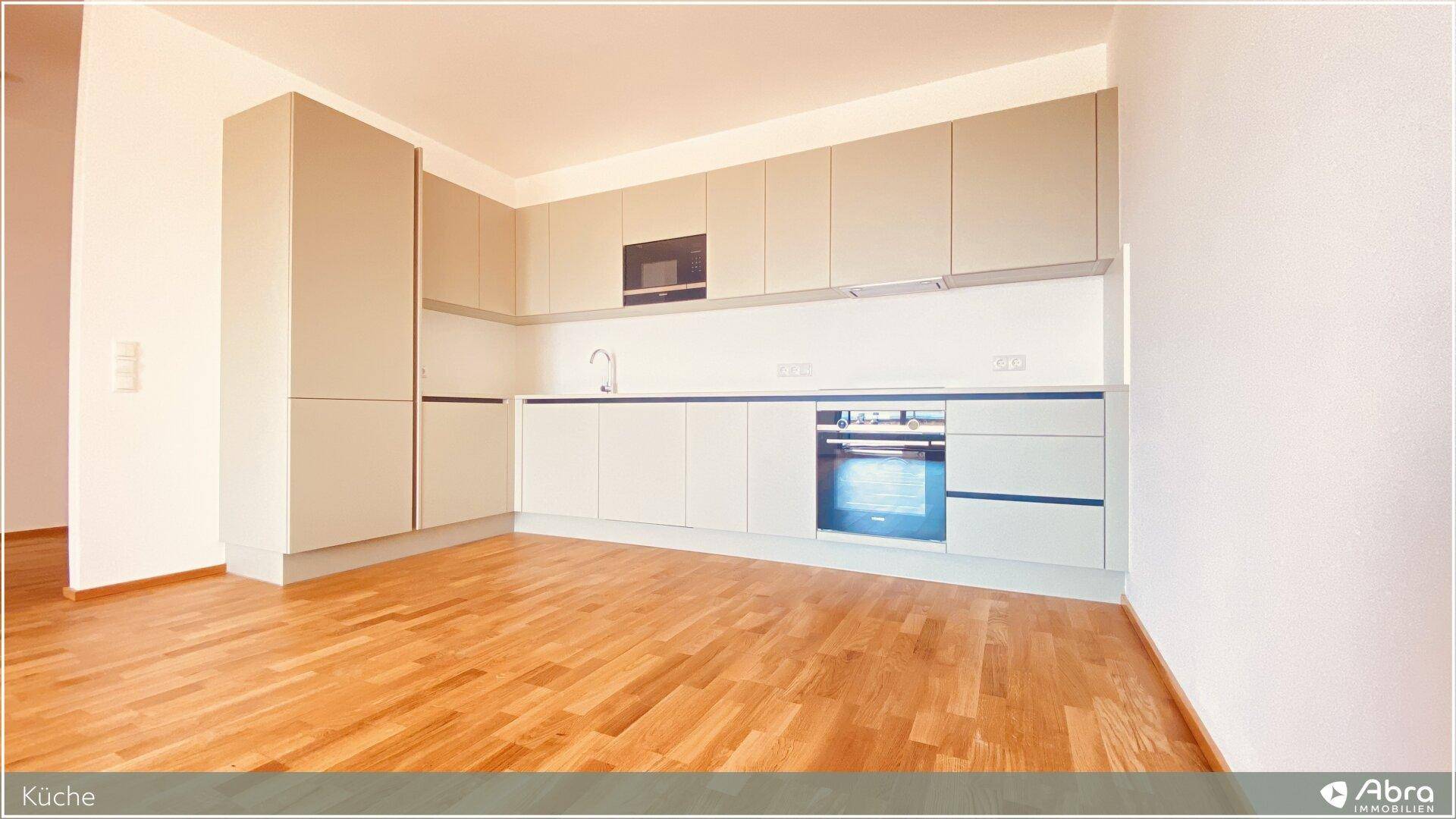Funktionale Einbauküche mit hellen Fronten, integrierten Geräten und Holzparkettboden.