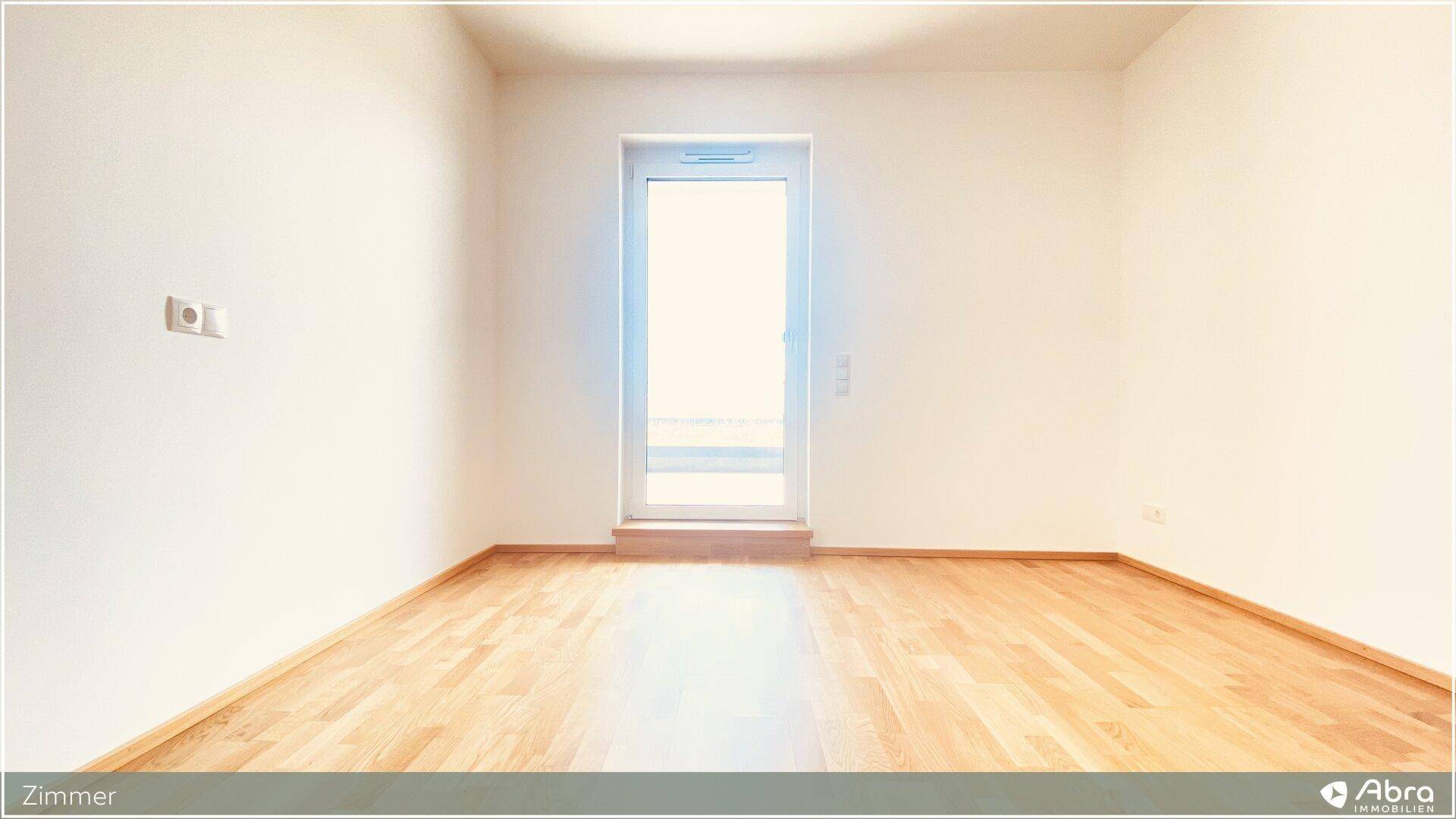Freundliches Zimmer mit Holzboden und einem großen Fenster, bereit zur individuellen Gestaltung.