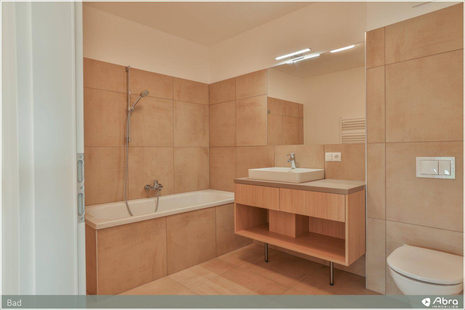 Modernes Badezimmer mit Badewanne, Einzelwaschbecken und großformatigen Fliesen.