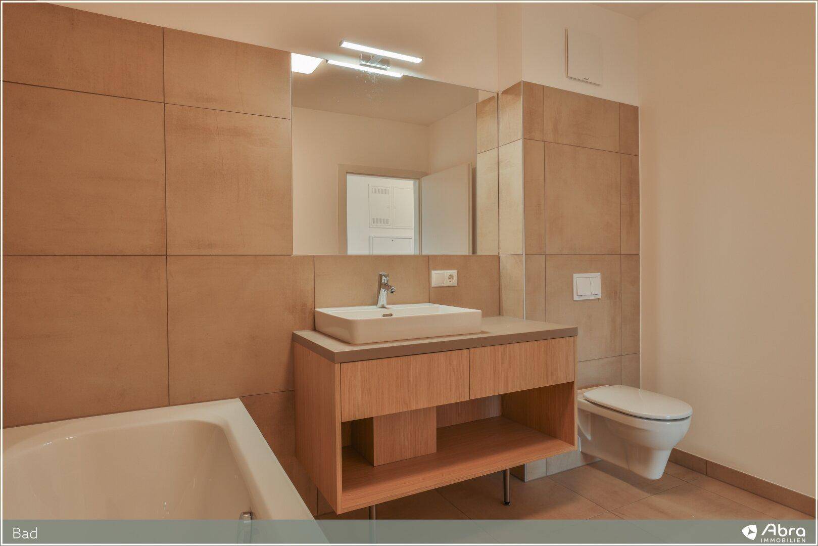 Helles Badezimmer mit modernem Waschtisch, Wand-WC und beigefarbenen Fliesen.