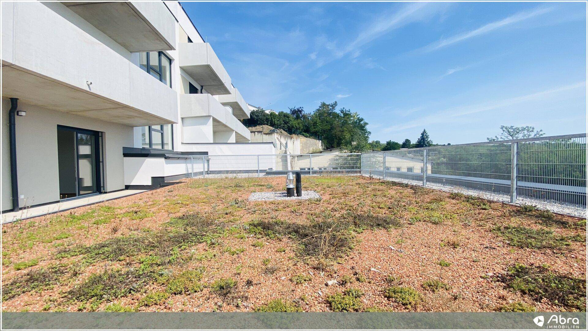 Begrünte Terrasse mit Blick auf die moderne Architektur des Gebäudes und die Umgebung.