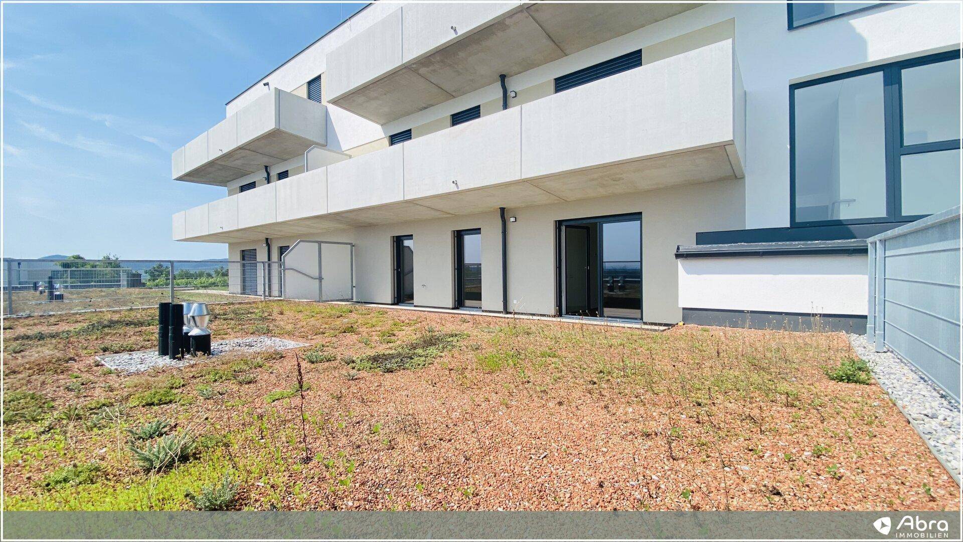 Ansicht der modernen Wohnanlage mit hellen Fassaden und einer großzügigen, begrünten Terrasse.