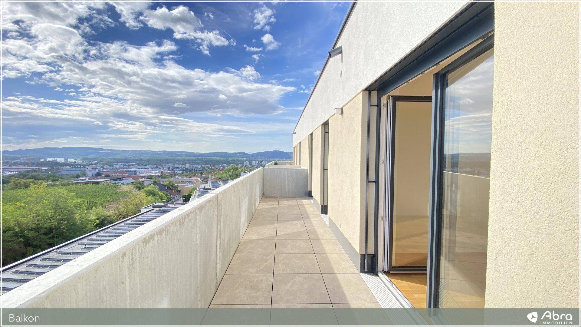 Langer Balkon mit Fliesenboden und Zugang zu den Innenräumen, bietet einen weiten Ausblick.