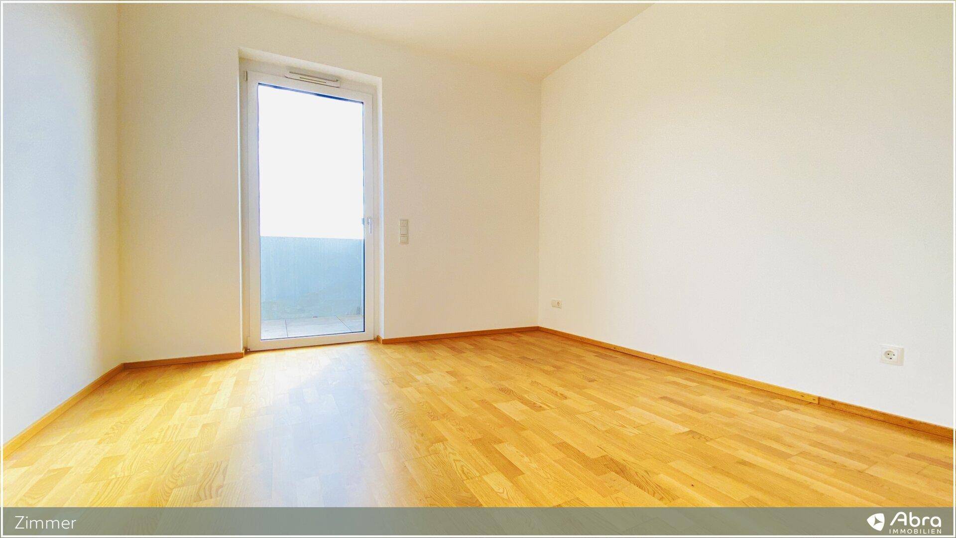 Helles Zimmer mit Parkettboden und Balkonzugang, bietet viel Tageslicht und frische Luft.