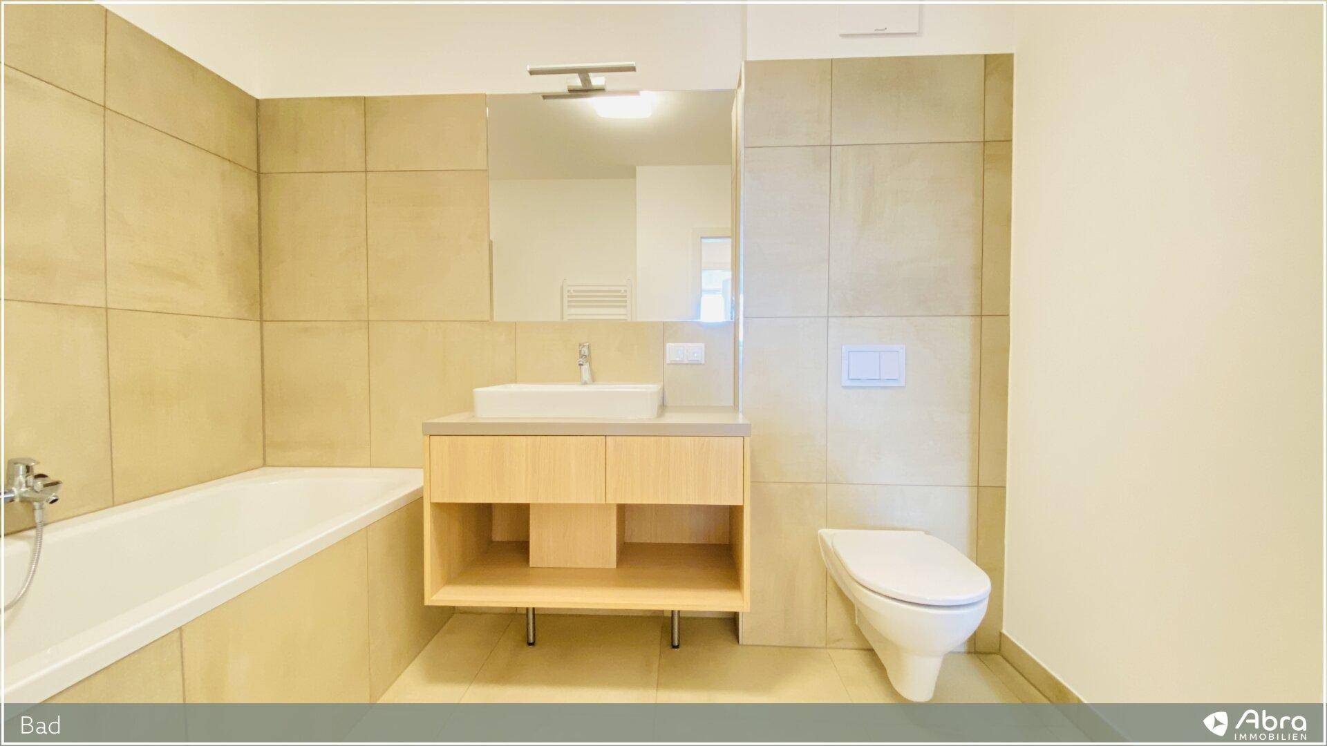 Modernes Badezimmer mit Badewanne, Waschtisch und Wand-WC, in neutralen Beigetönen gehalten.