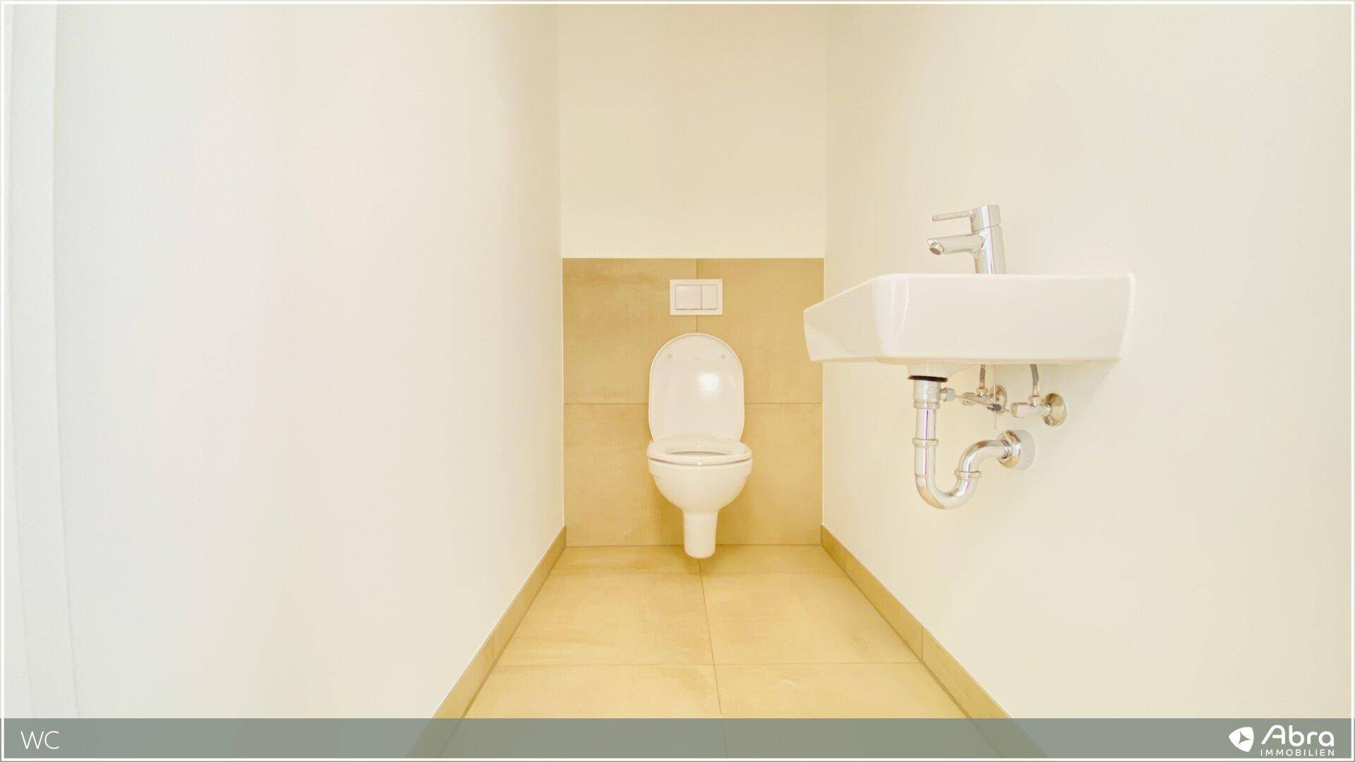 Separates Gäste-WC mit Wand-WC und kleinem Handwaschbecken, in schlichtem Design.