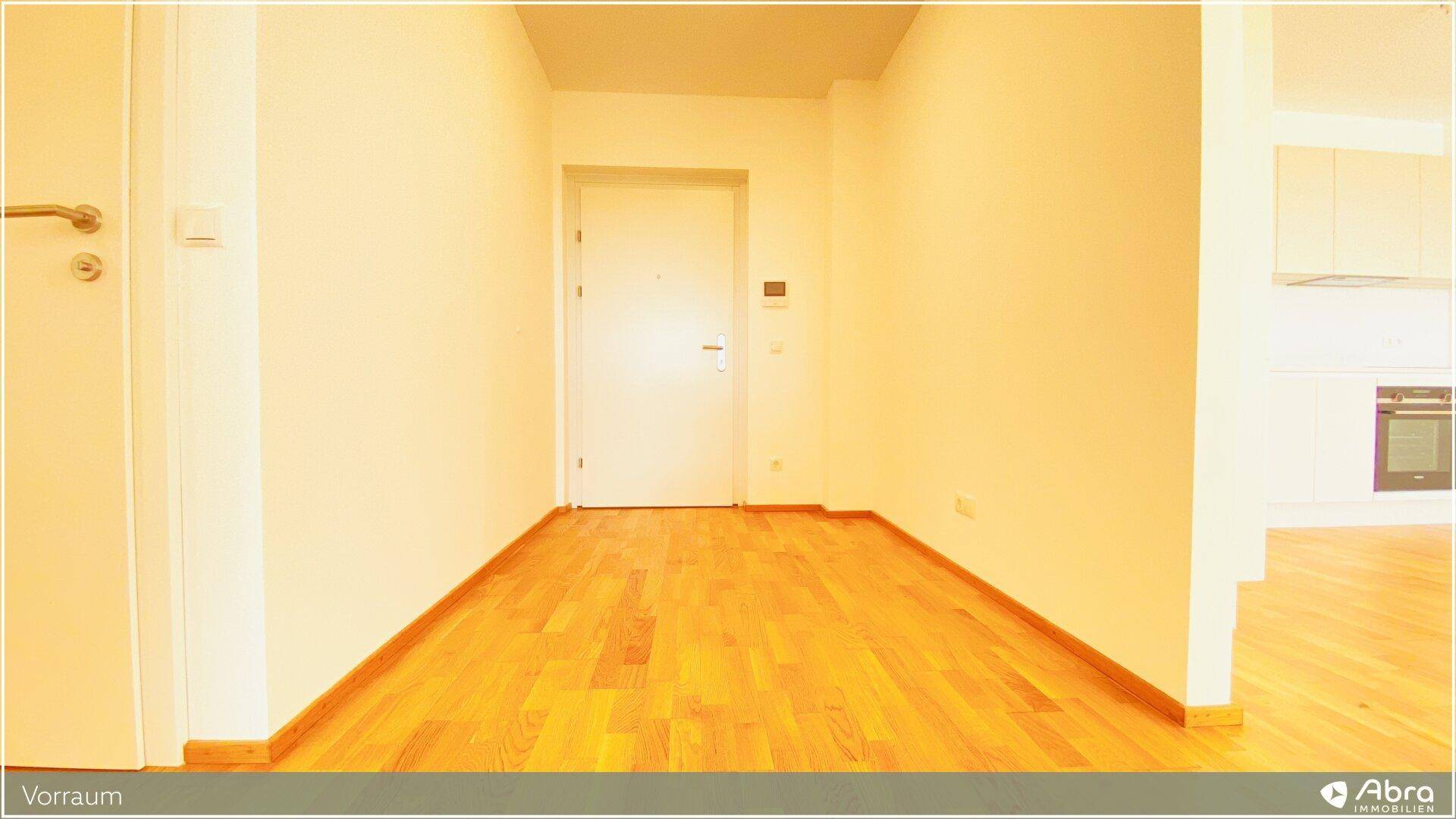 Eingangsbereich mit Parkettboden und weißer Tür, führt in die weiteren Räume der Wohnung.