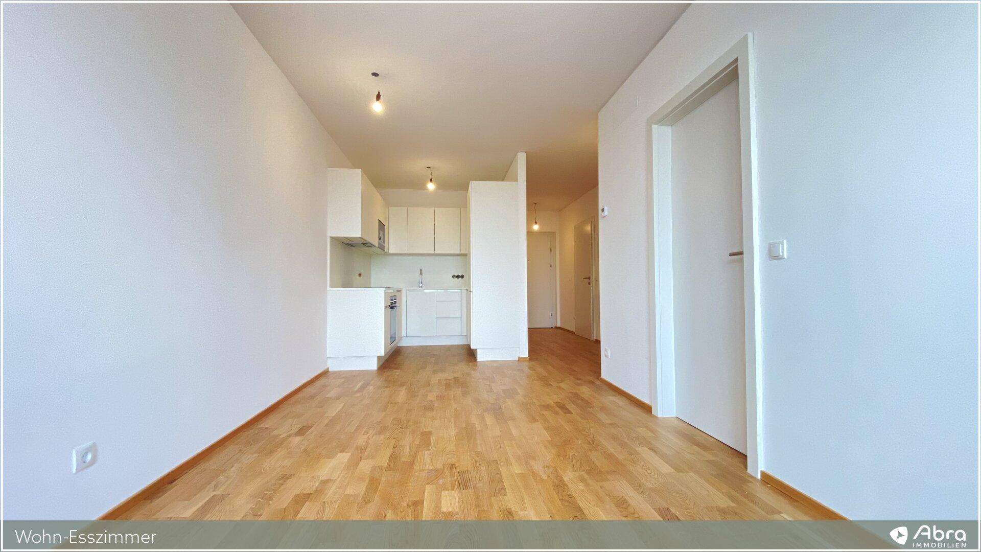 Heller Wohn-Essbereich mit offener Küchenzeile und hellem Holzparkettboden, ideal für modernes Wohnen.